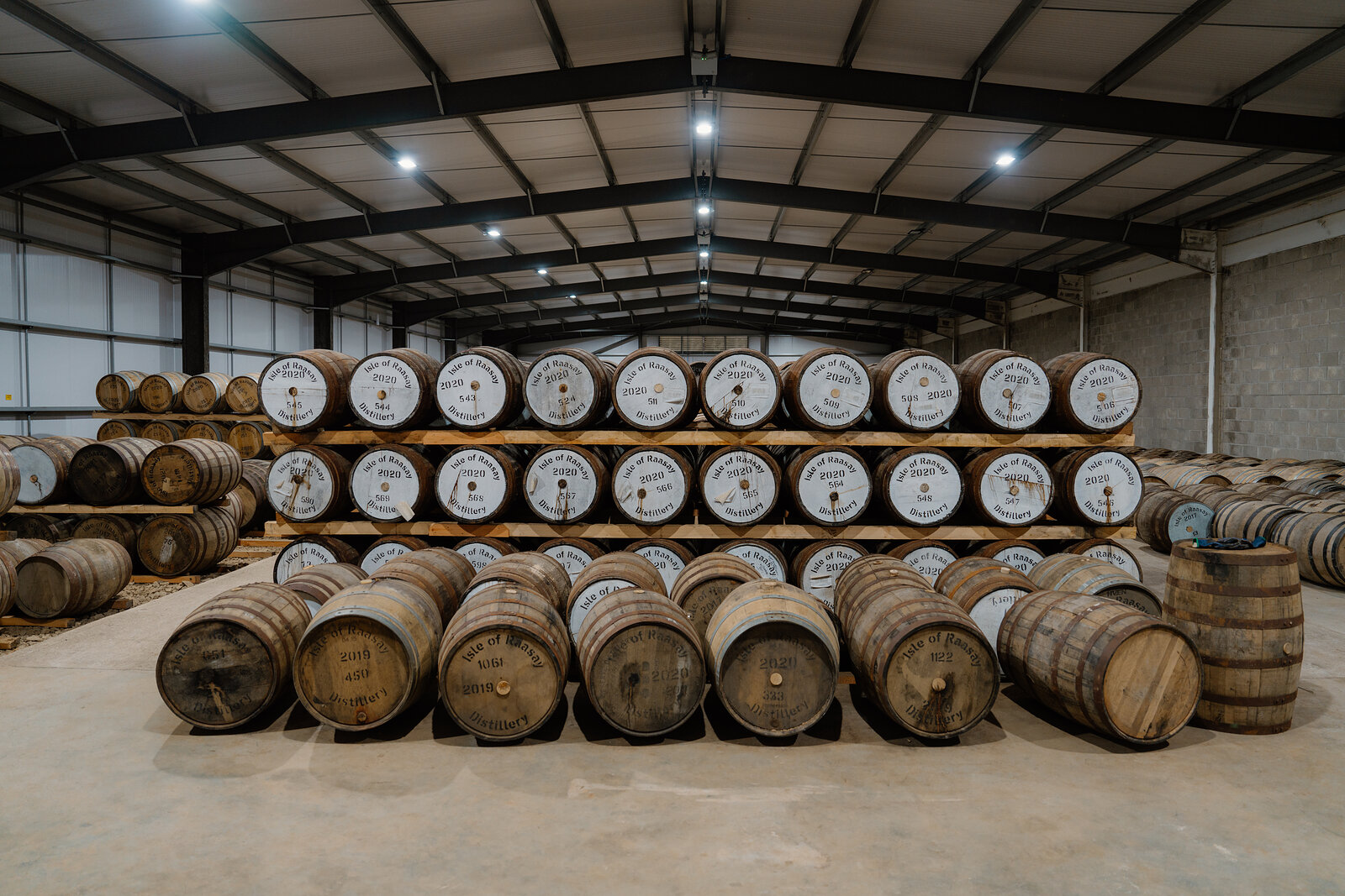 Racked and floor-stacked whisky casks fill a warehouse at the Isle of Raasay Distillery.