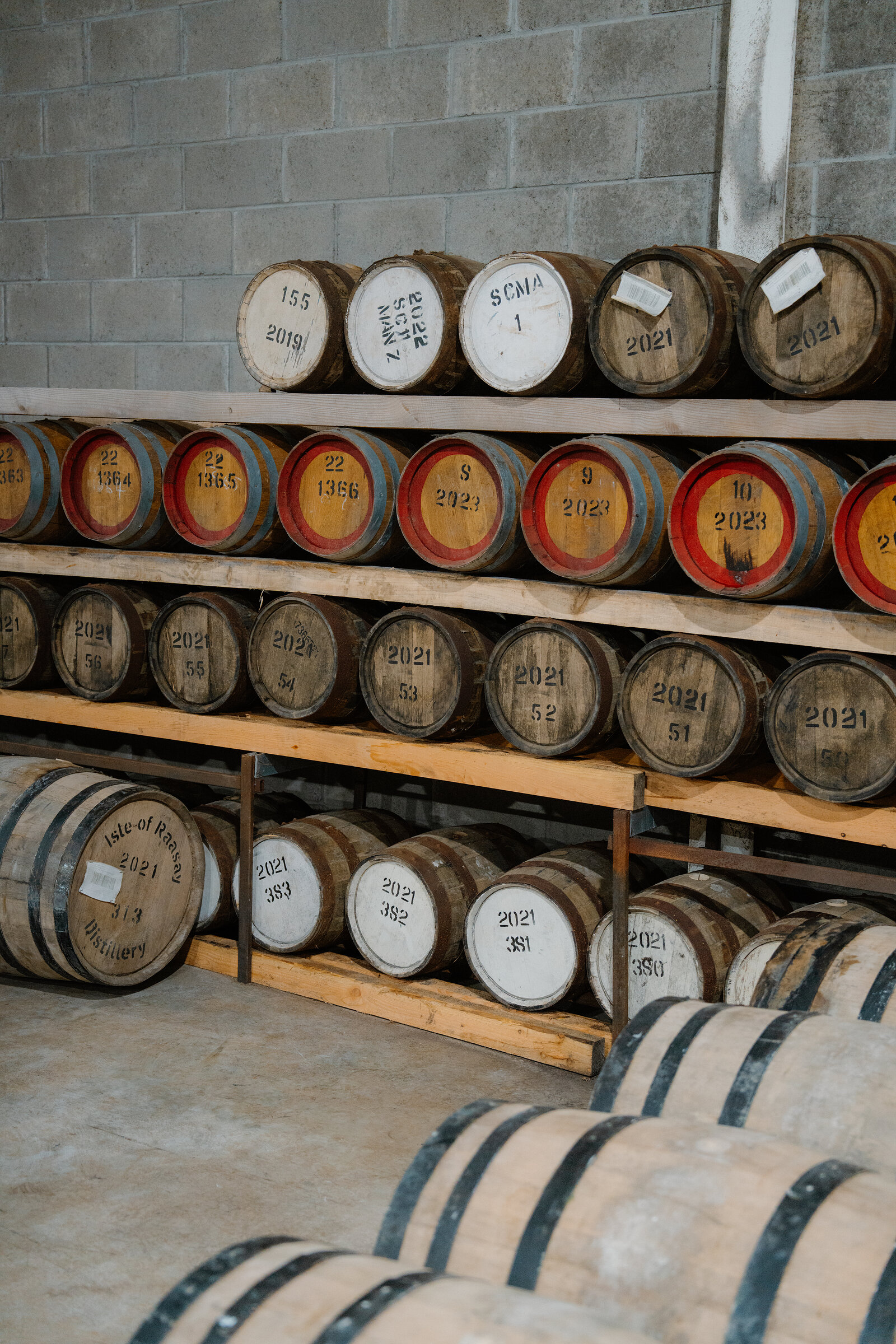 Whisky casks labelled Isle of Raasay Distillery are racked and stacked in a warehouse.