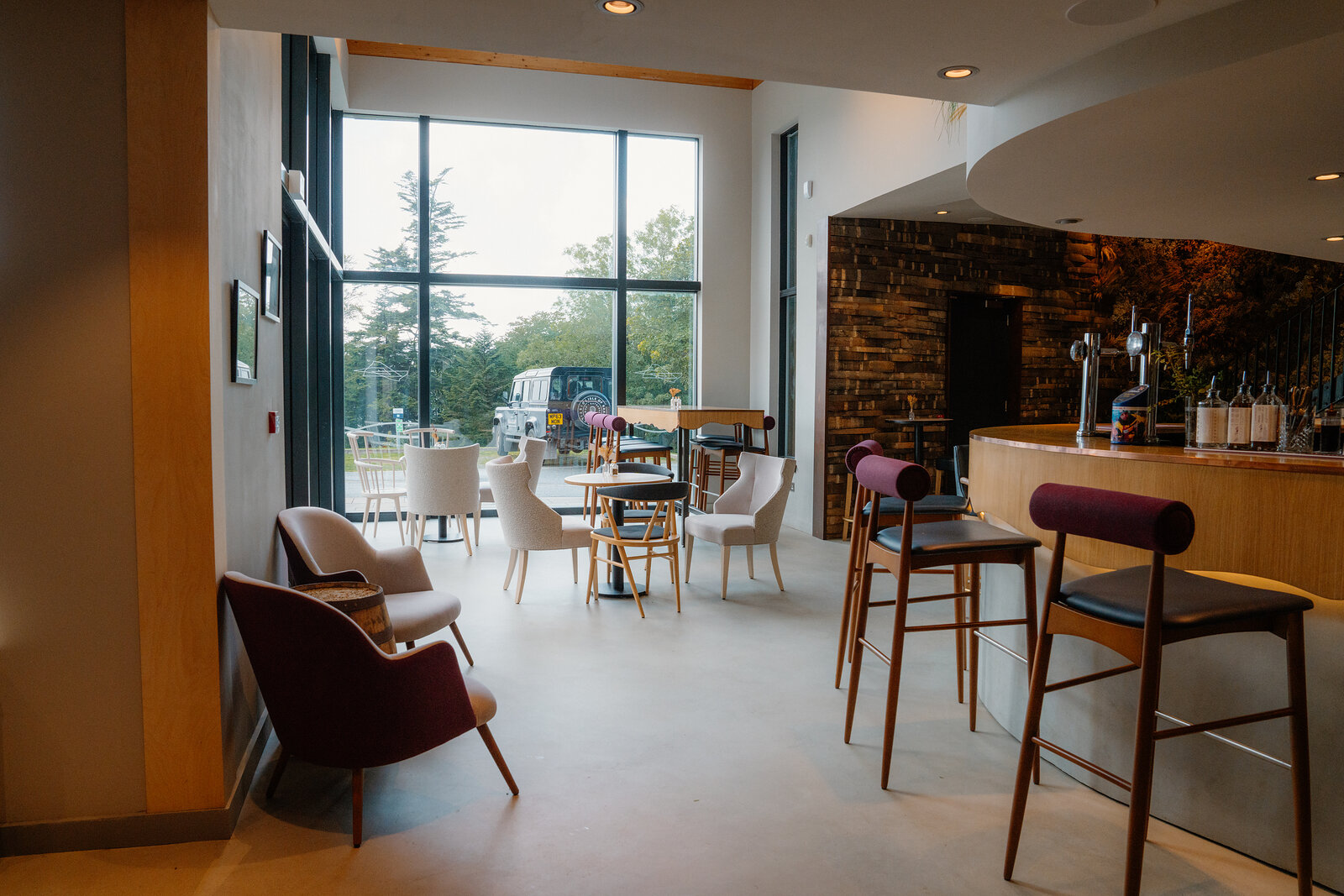A stone-walled bar and lounge seating sit beneath pendant lights at the Isle of Raasay Distillery.