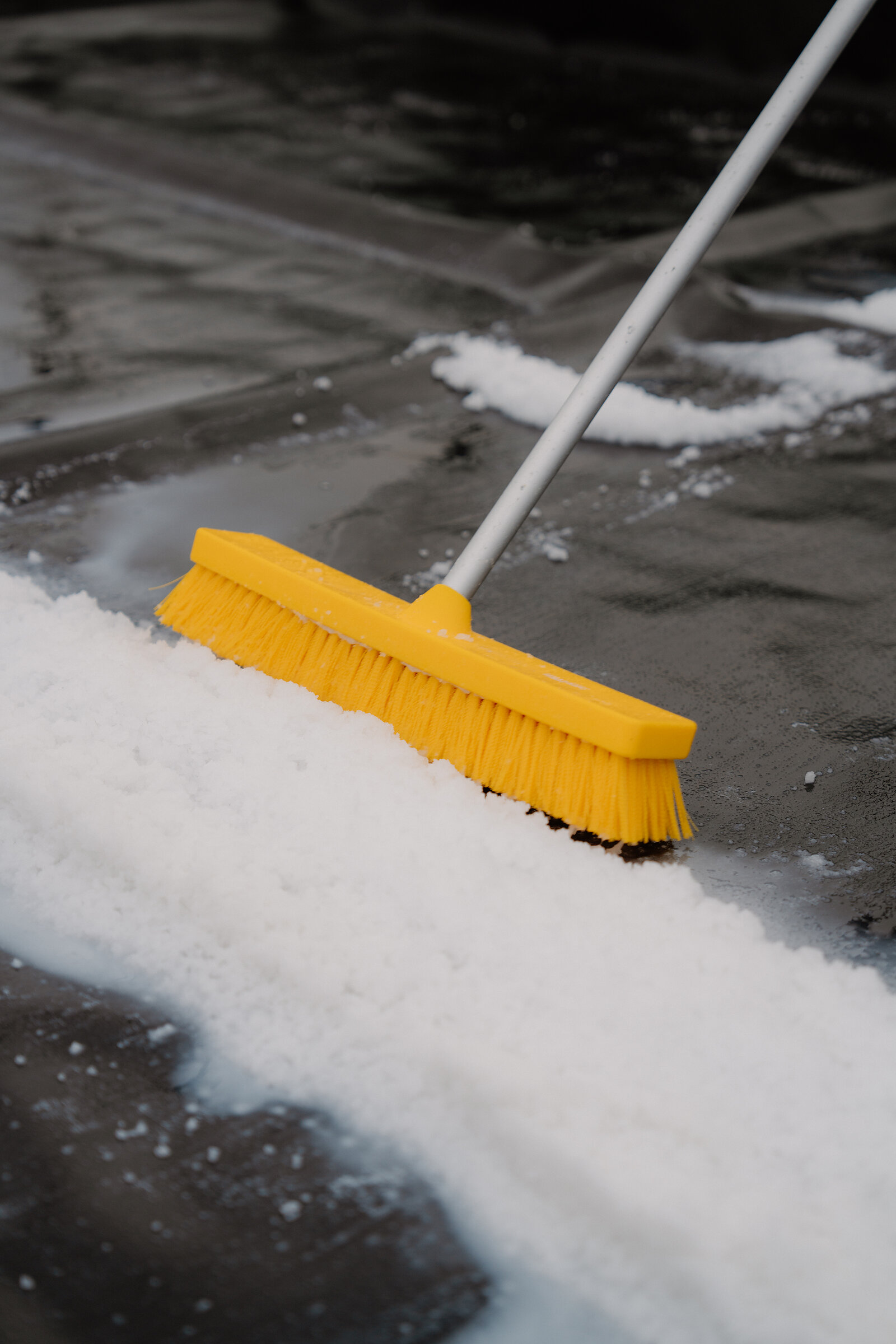 A yellow-bristled broom sweeps slush from a polytunnel's dark floor at the Isle of Skye Sea Salt Company.