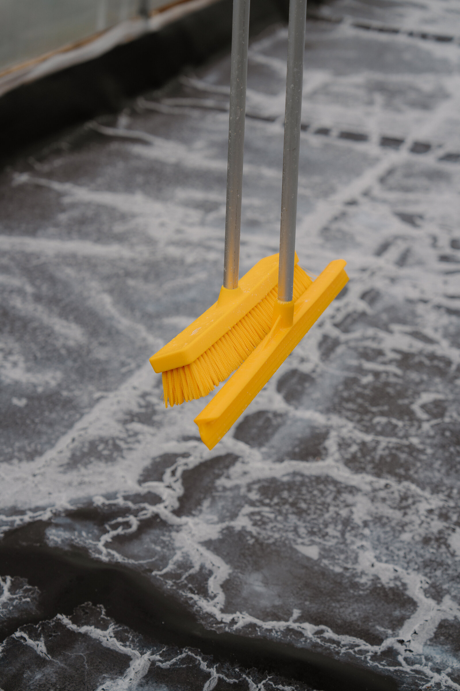 Two yellow-bristled brushes rest on a salt-crusted polytunnel floor at the Isle of Skye Sea Salt Company.