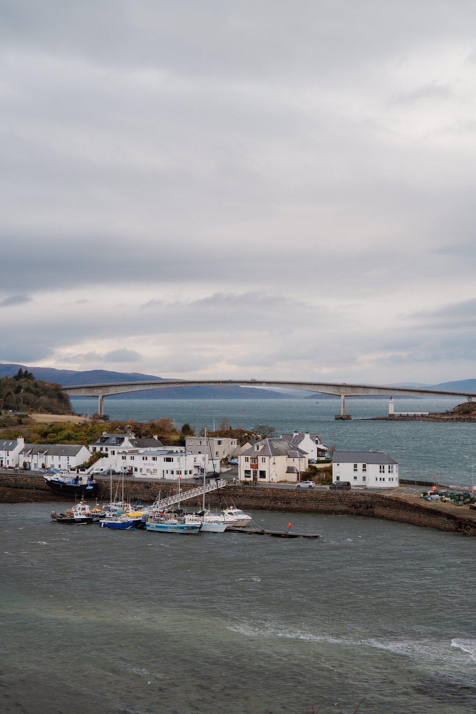 The Skye Bridge spans the strait beyond Kyleakin's harbour and white houses.