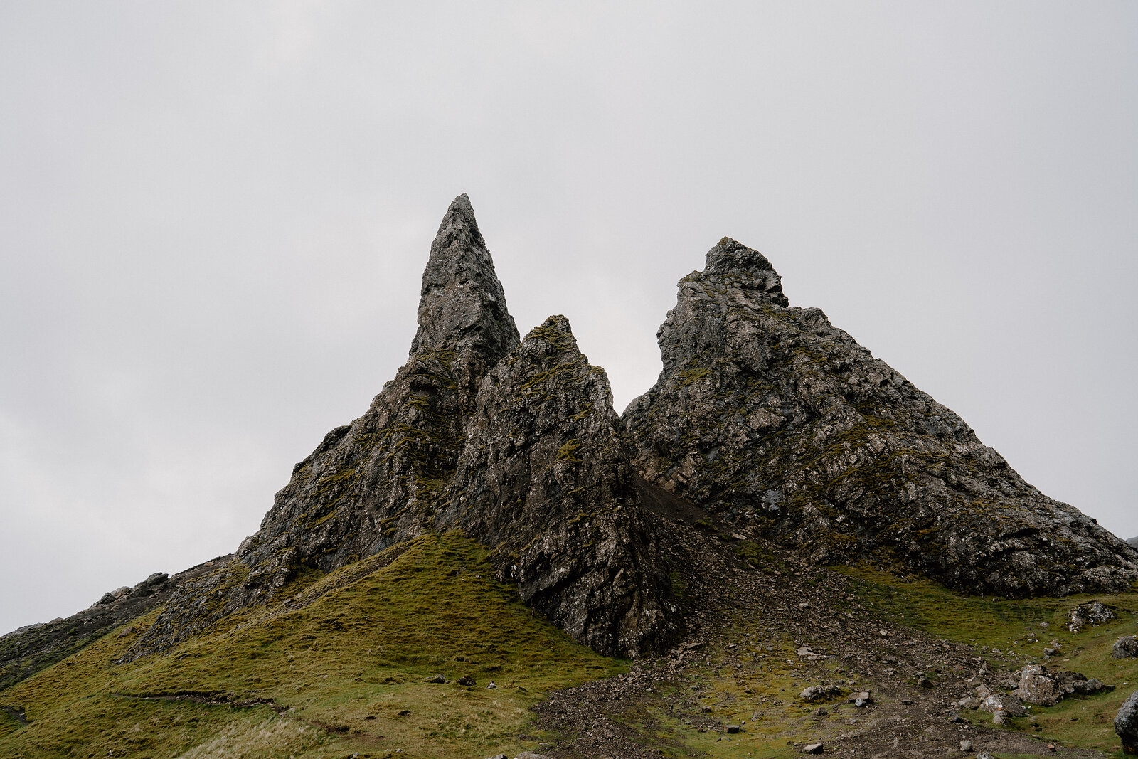 The Old Man of Storr's pinnacles rise above a grassy hillside on the Isle of Skye.