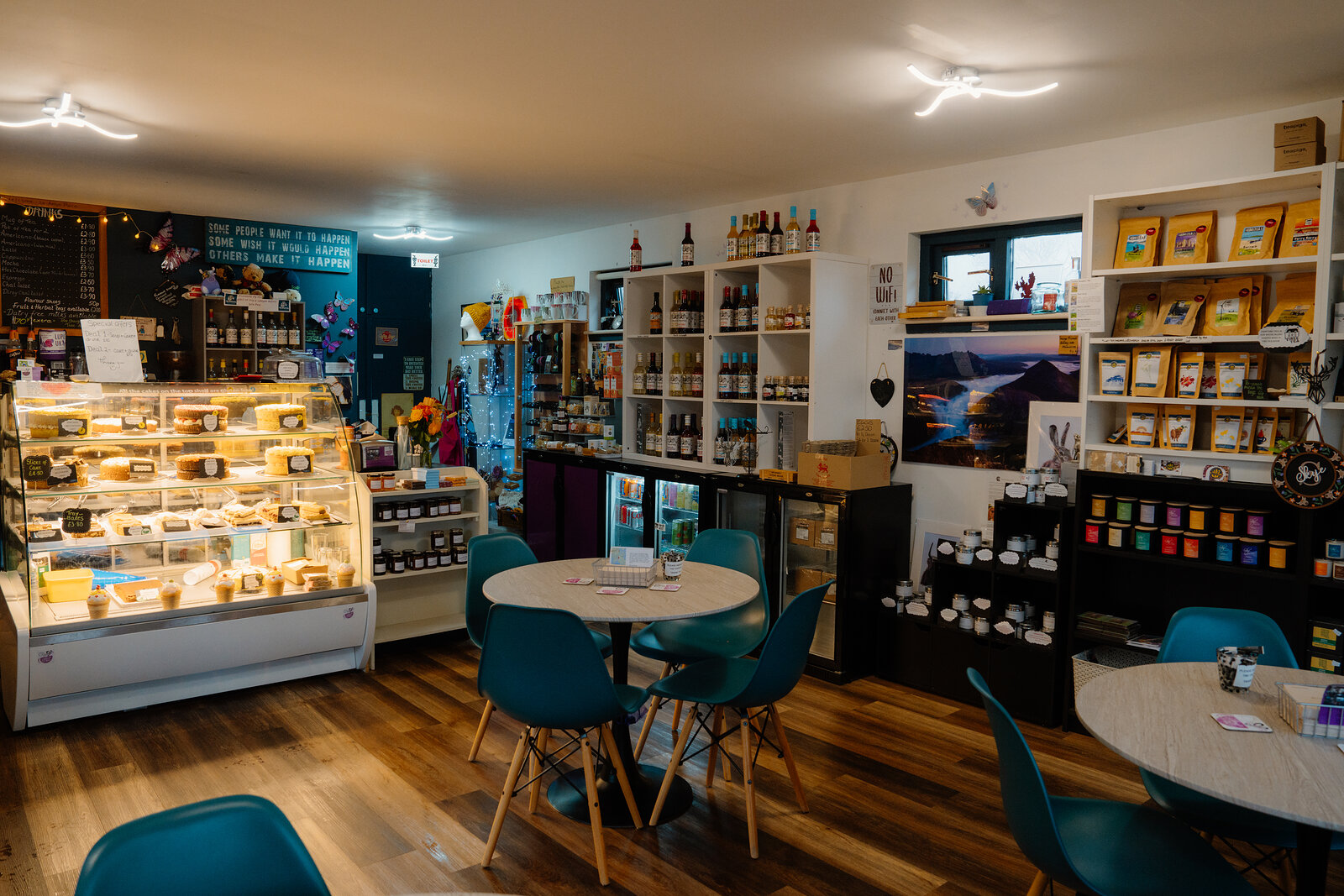 Amy's Place Tea Room's cake counter and gift shelves fill a room furnished with teal chairs and round tables.