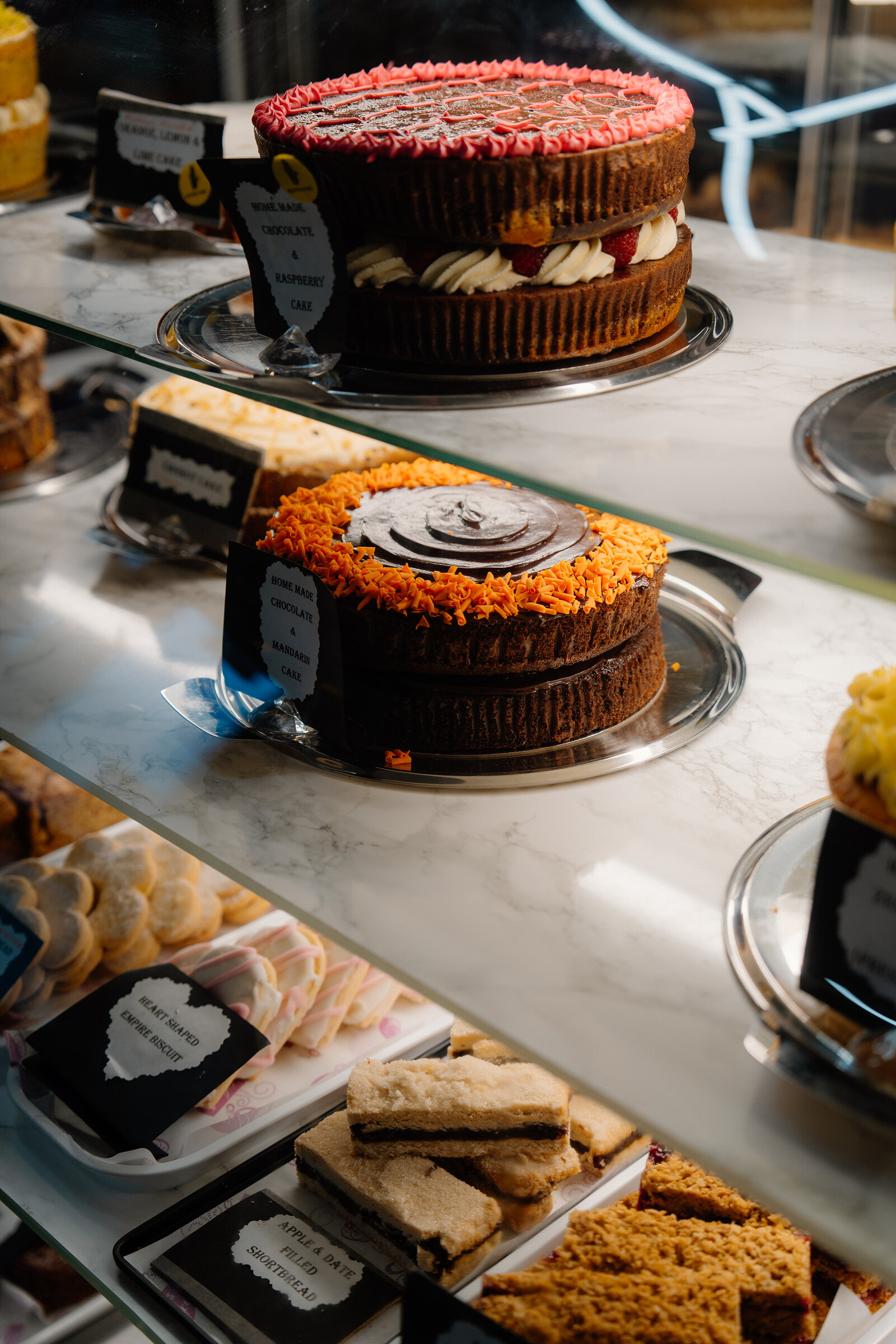 A glass display counter at Amy's Place Tea Room holds a tiered cheesecake, jars of preserves and other cakes.