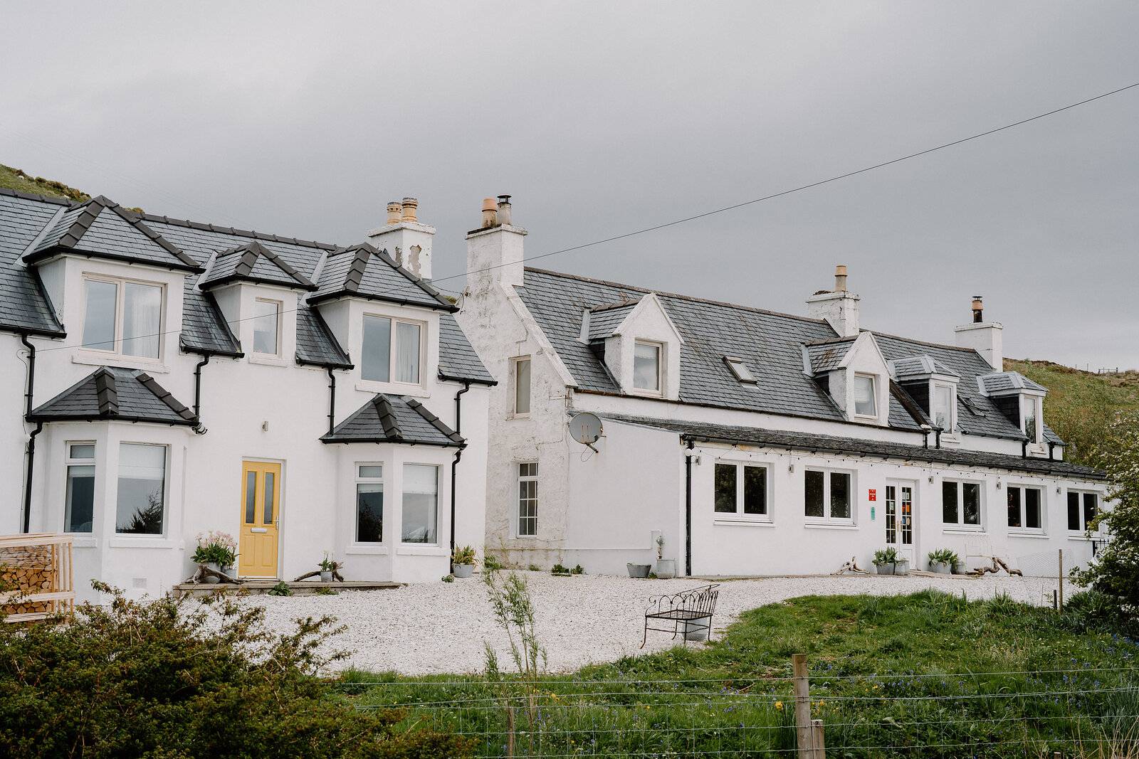 Coruisk House's white harled exterior shows dormer windows and clustered chimneys against a grey sky.