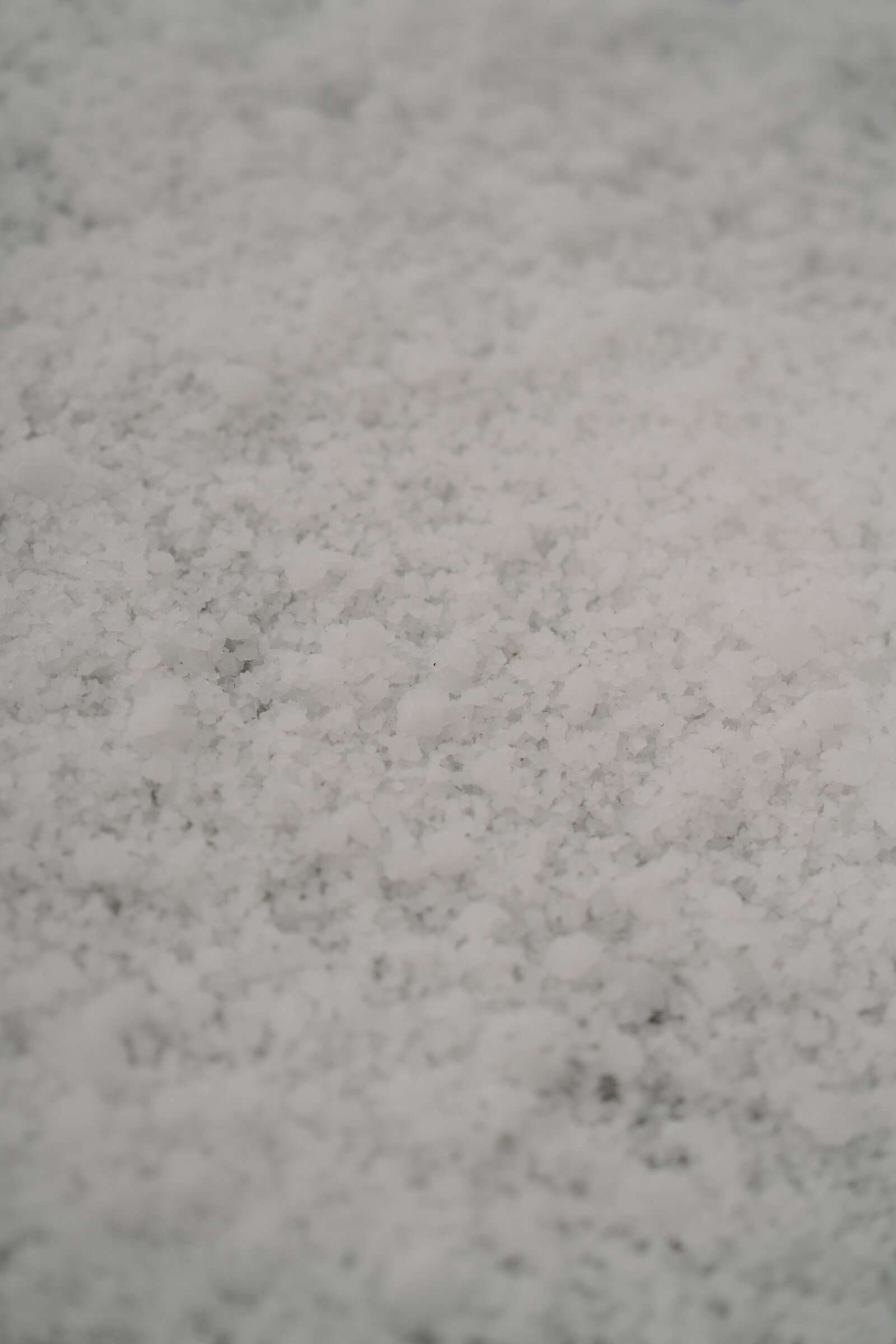 Damp white salt crystals cover a dark tarpaulin at Isle of Skye Sea Salt Company.