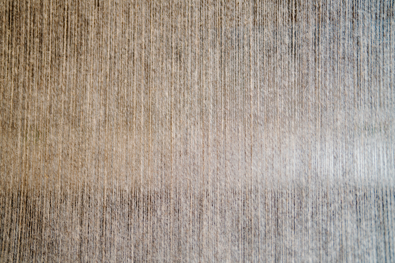Close texture of woven grey tweed fabric on a loom at Skye Weavers.