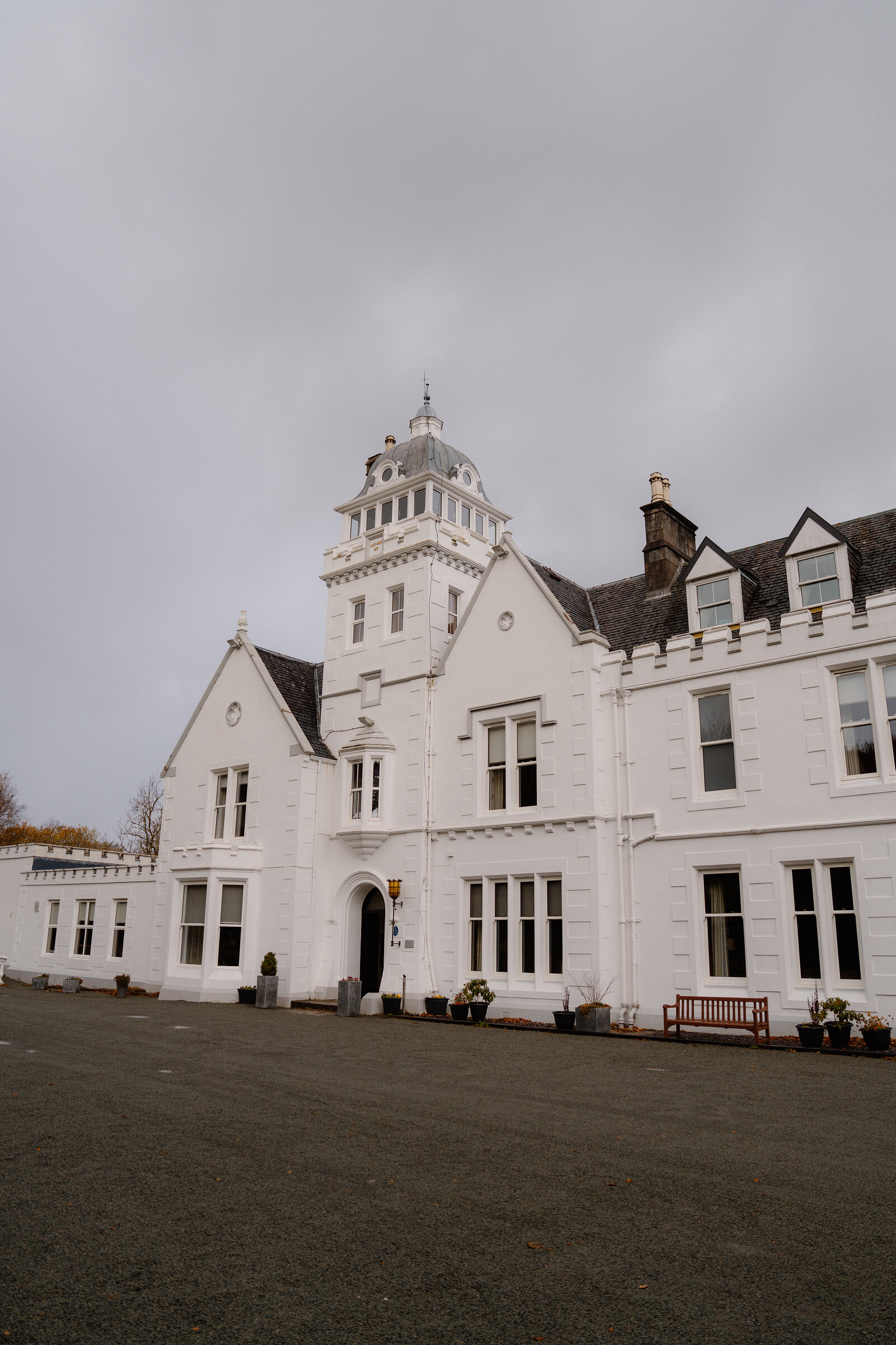 Skeabost's white mansion rises to a tower with a pointed roof above a gravel forecourt, part of the Sonas Collection.