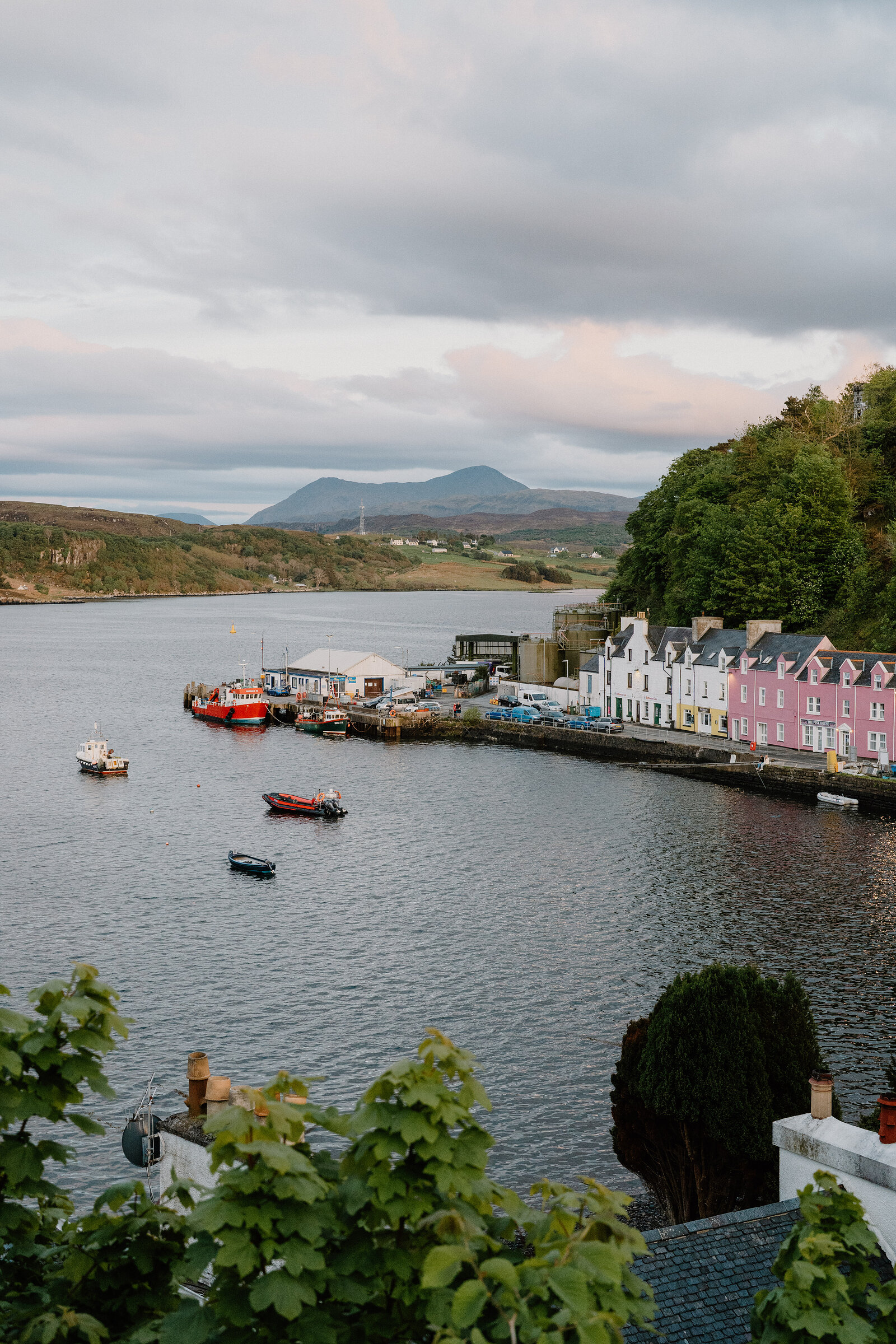 Portree's coloured houses curve along the harbourfront, boats moored before distant mountains.