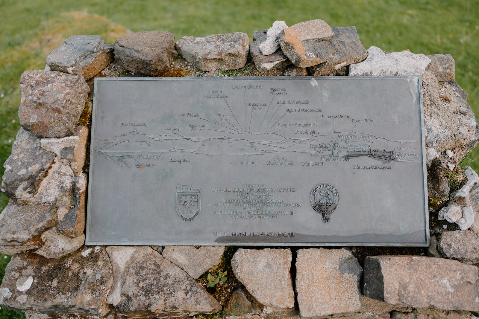 A weathered map plaque set in a stone cairn marks a route across the landscape.