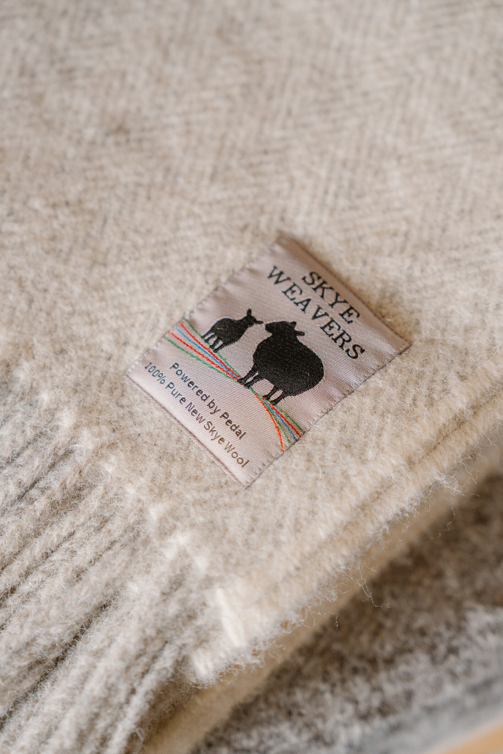 A 'Skye Weavers' label reading 'Powered by Pedal' is stitched onto a cream woven throw.