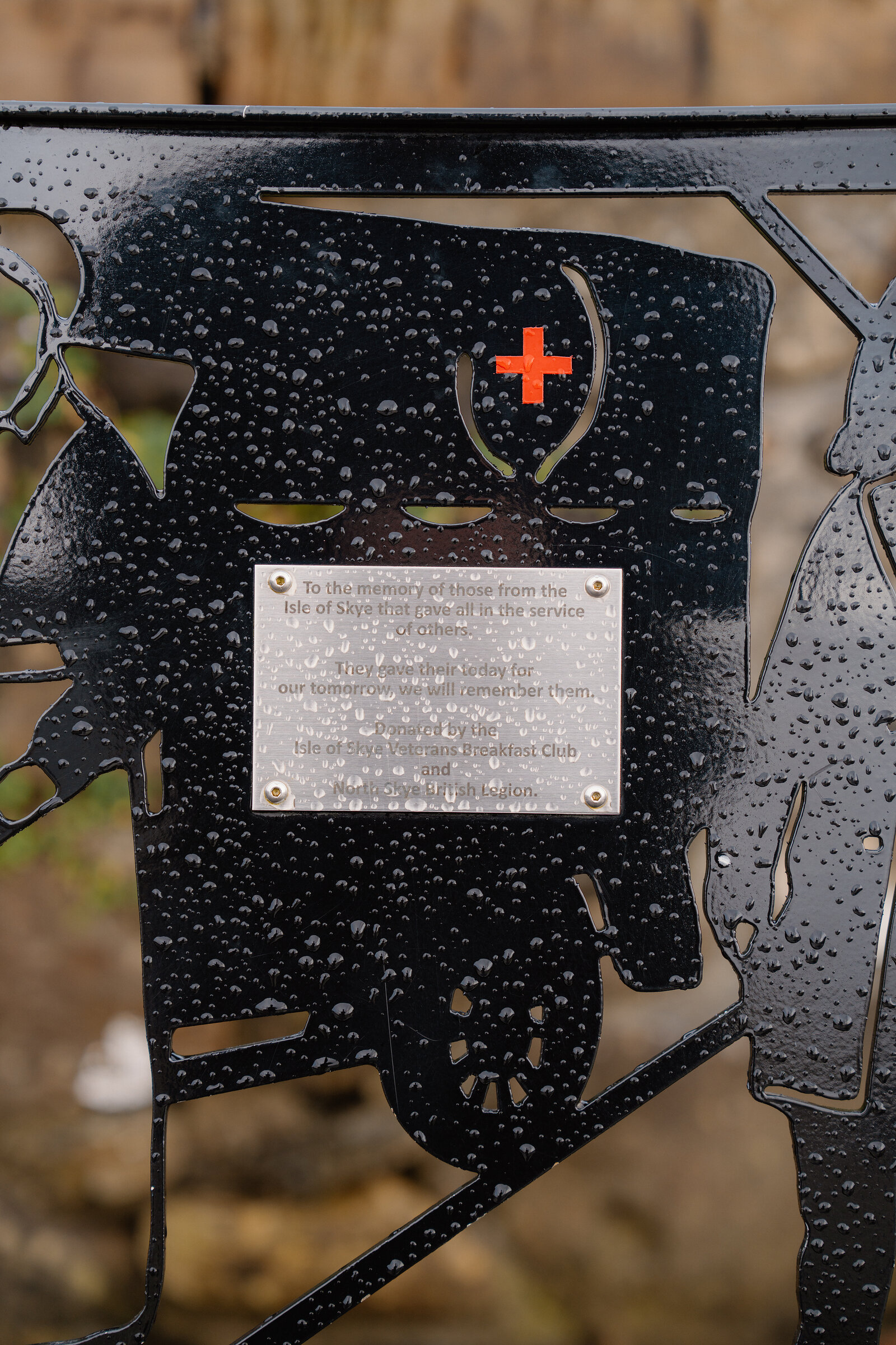 A rain-speckled metal plaque set into a bench commemorates those lost at sea.