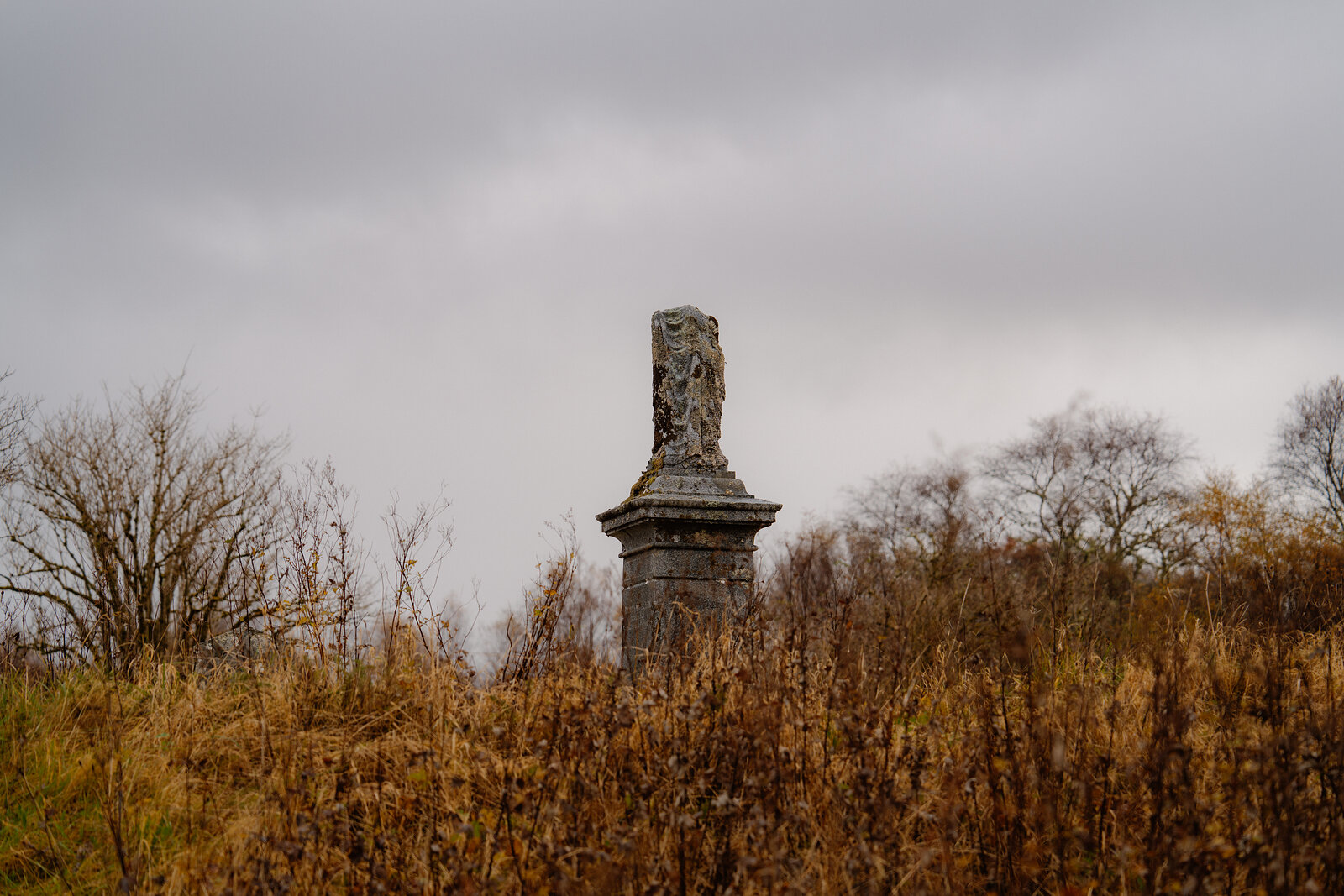 A tall carved memorial column stands among autumn scrub and grass at St Columba's Island.