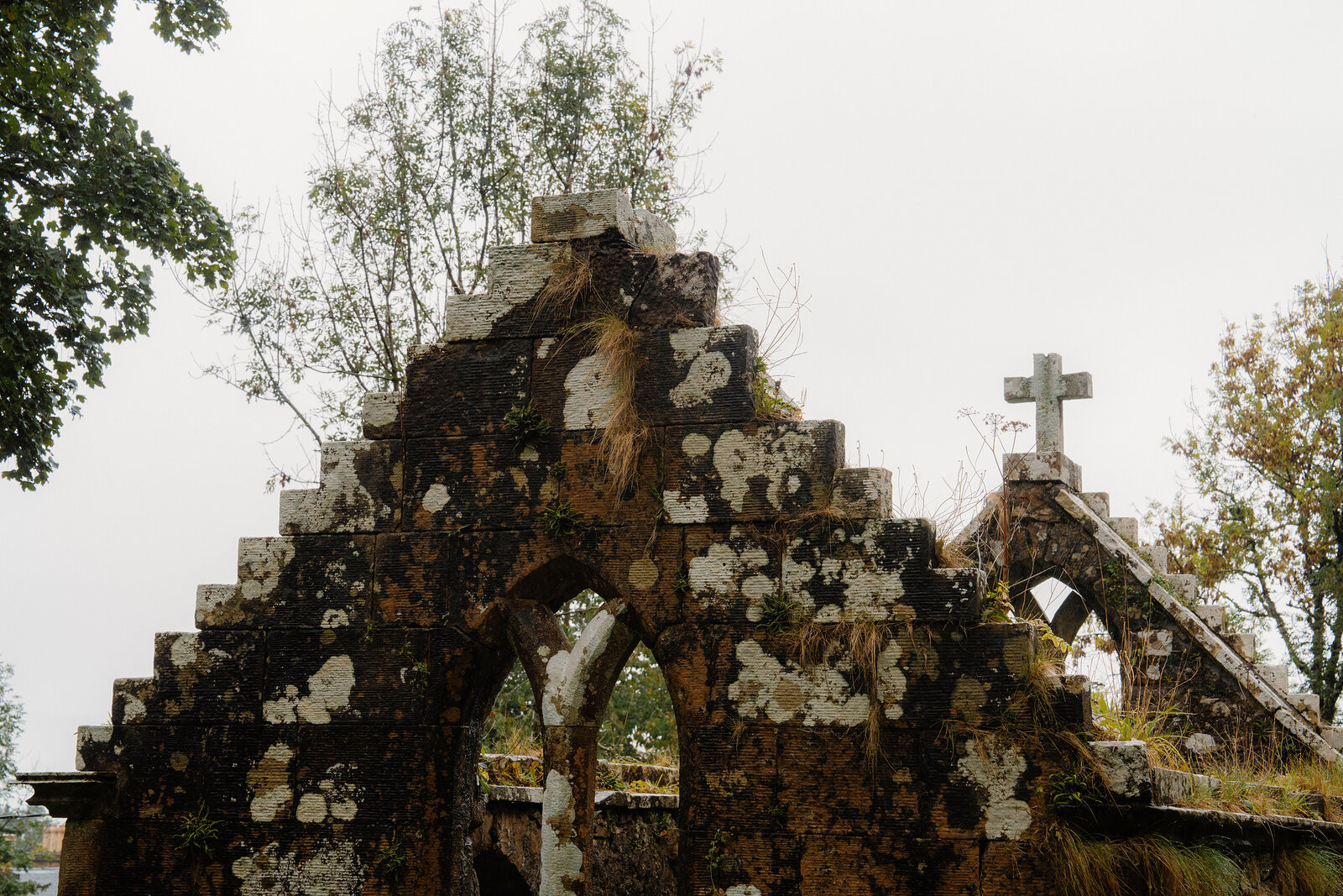 The stepped gable of the MacLeod vault at St Moluag's, lichen on the stone, a second cross among the trees.