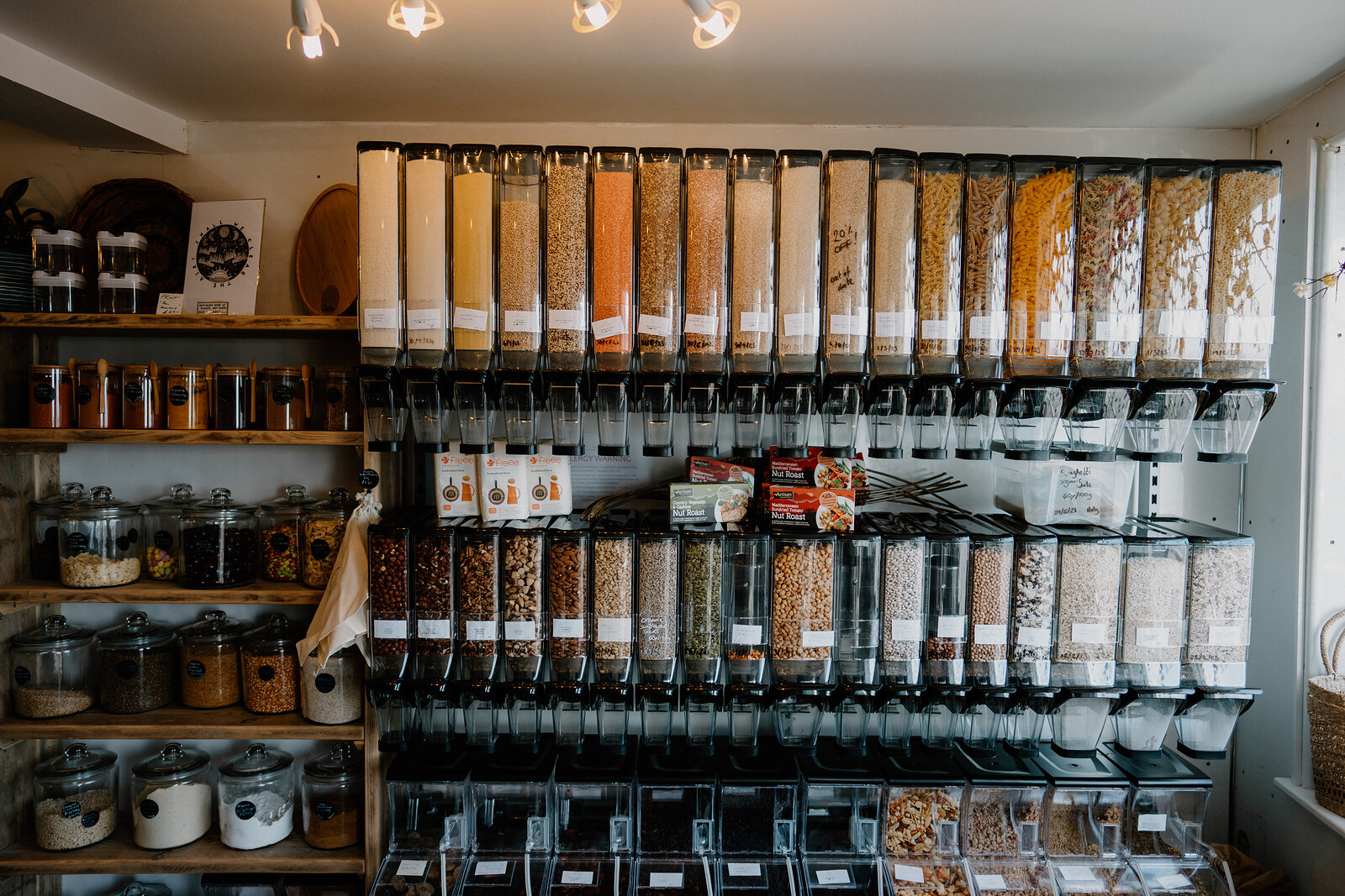 Rows of bulk-food dispensers filled with grains, nuts and dried goods line a shop wall.