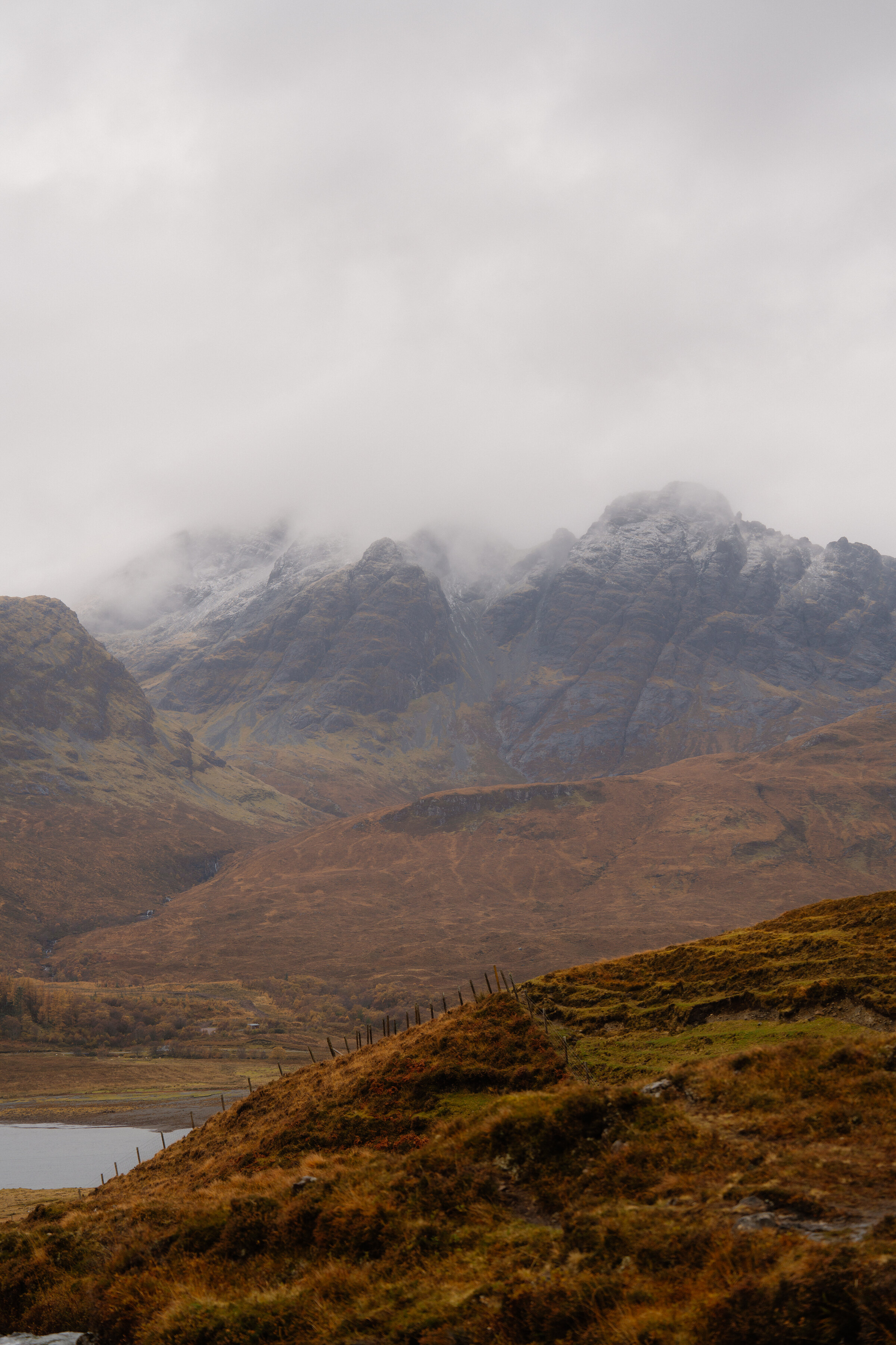 Blà Bheinn's crags under a dusting of snow, the top in cloud above russet moorland.