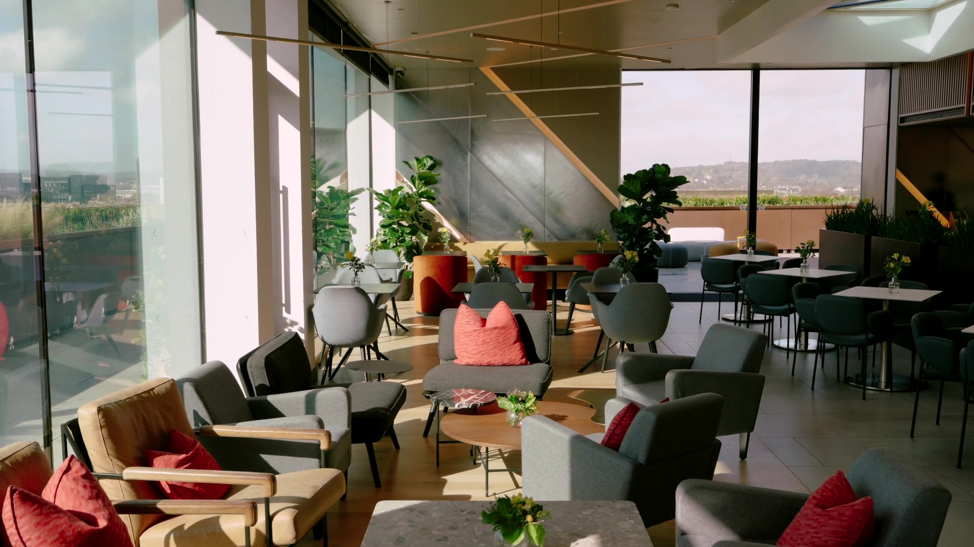 A rooftop lounge with red cushioned chairs and potted fig trees overlooking the city from the Johnnie Walker Experience