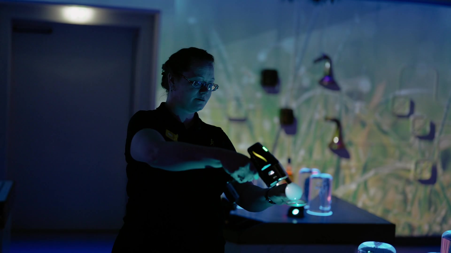 A guide pouring a whisky sample at a UV-lit tasting table