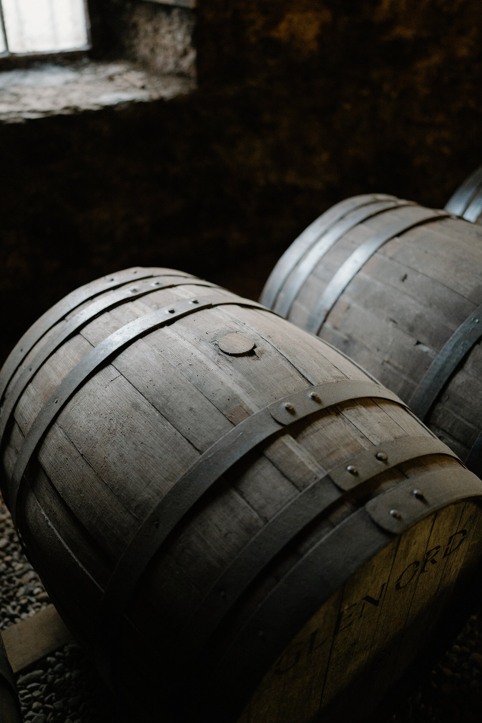 Whisky casks branded 'Glen Ord' are stacked in a dimly lit warehouse.