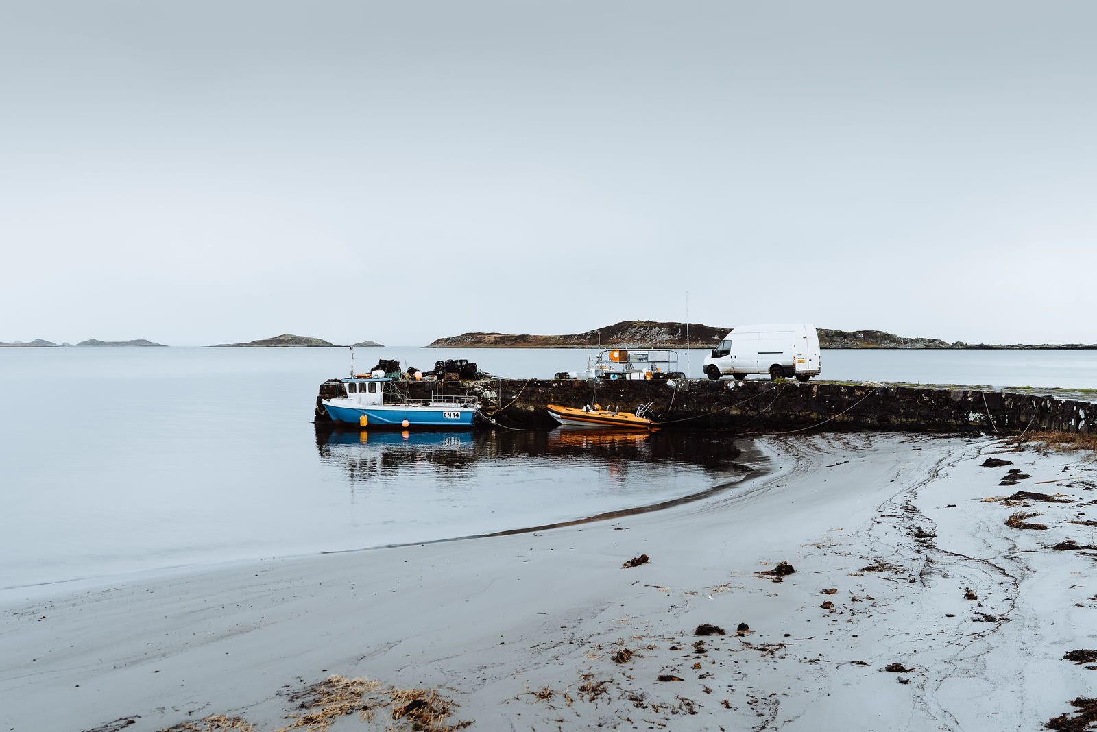 Fishing boats at the stone pier in Craighouse at low tide.