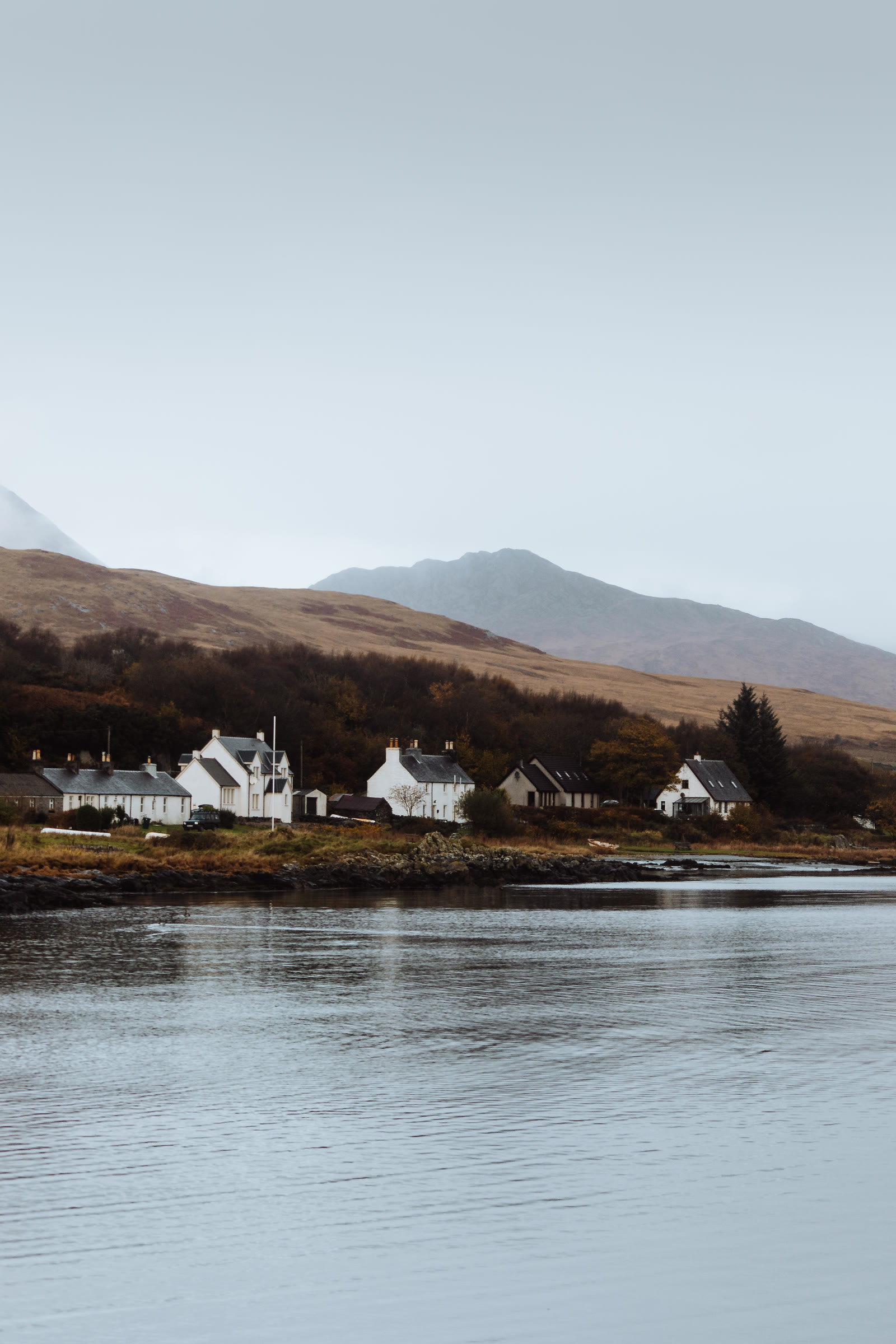 White houses on the shore at Craighouse, hills behind.