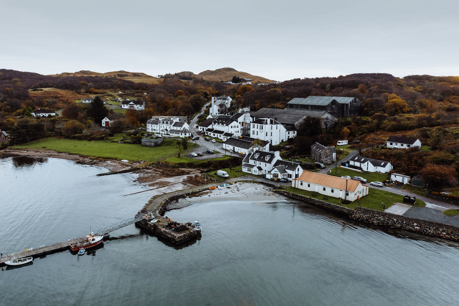 The stone pier, hotel and distillery at Craighouse from the air.