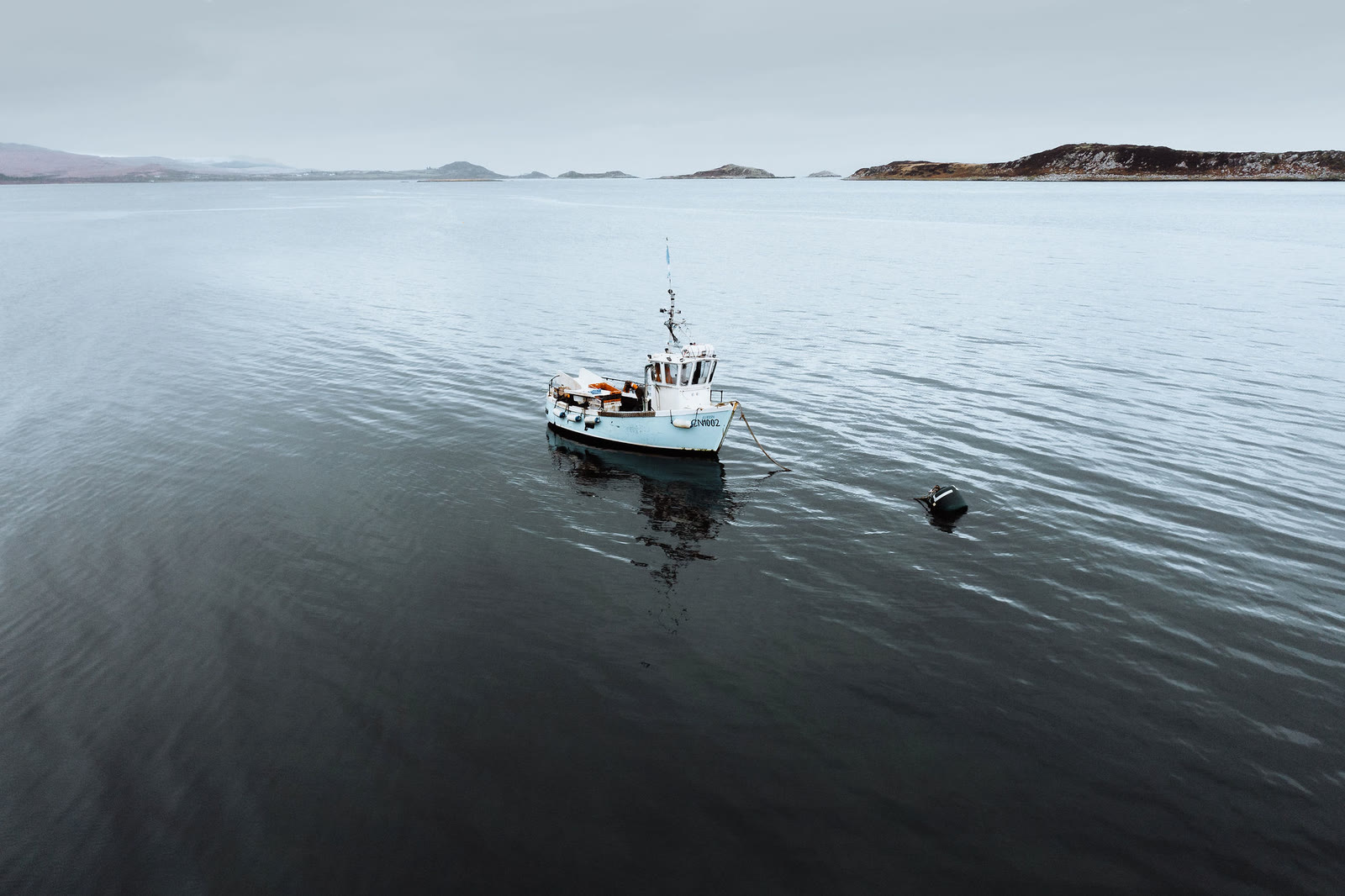A fishing boat at anchor on calm water in Small Isles Bay.
