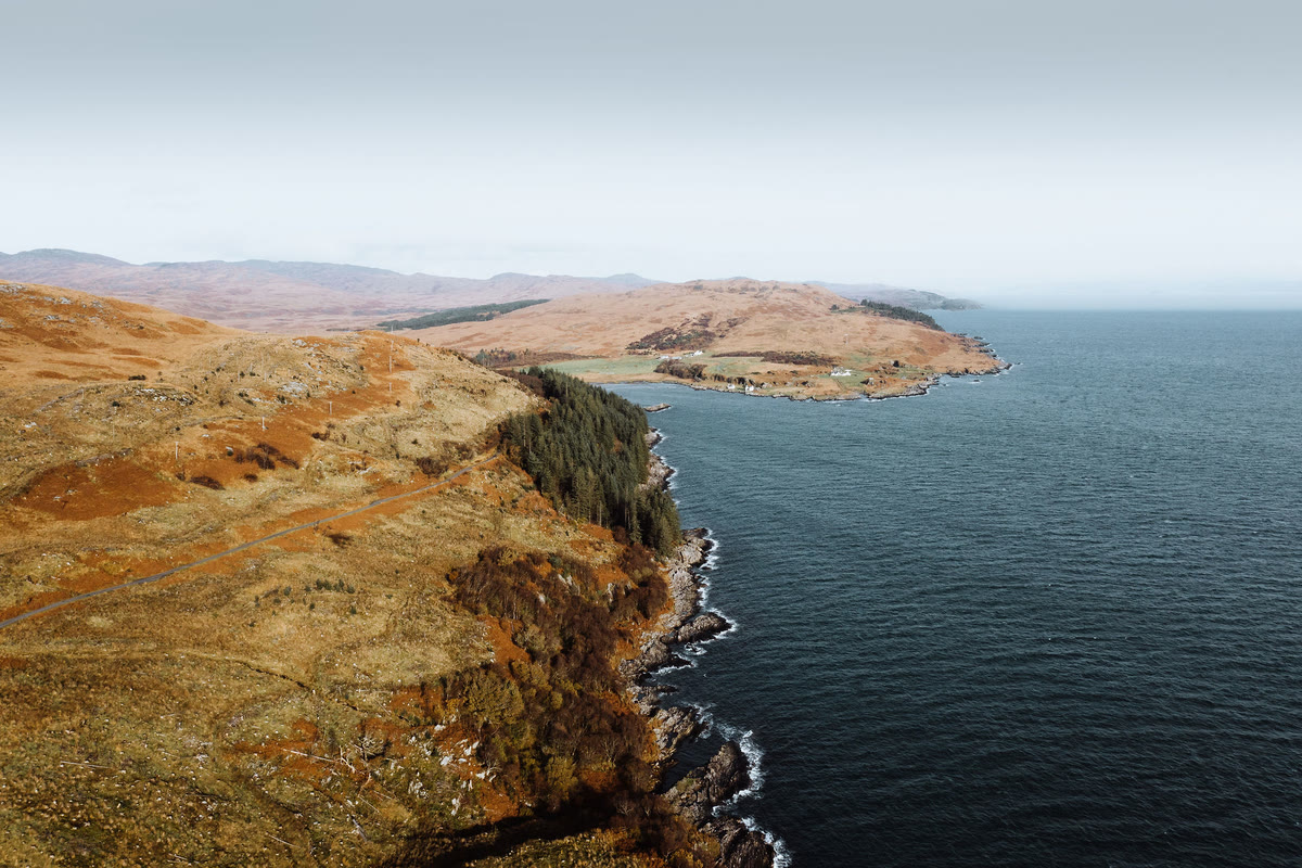 Cliffs and moor on Jura's coast from the air, a bay beyond.