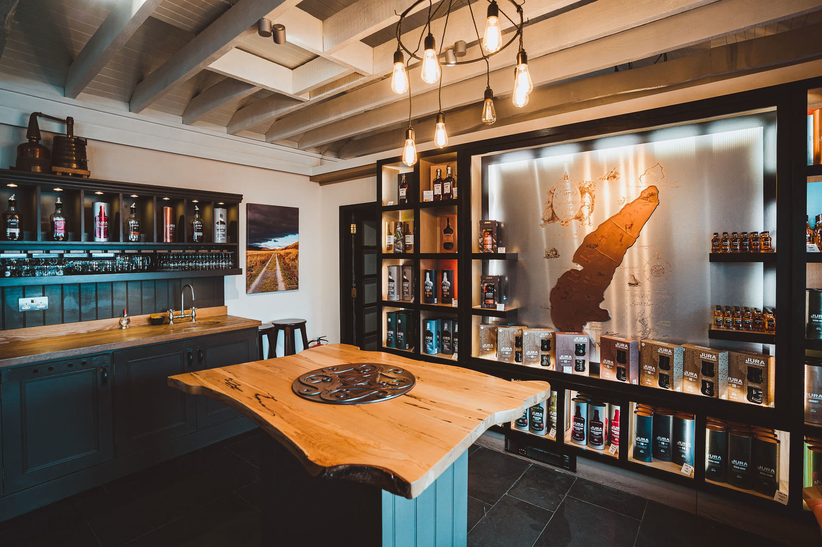 The distillery shop: a wooden table and lit shelves around a map of Jura.