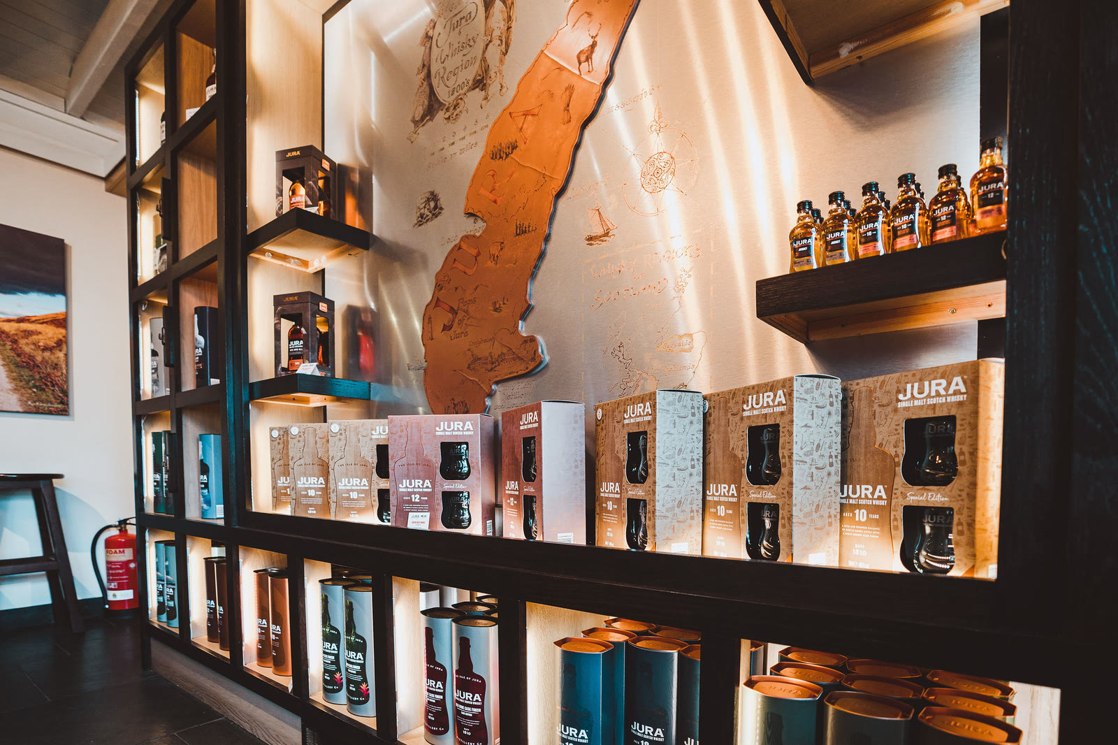 Boxed Jura whiskies on lit shelves around a wooden map of the island.