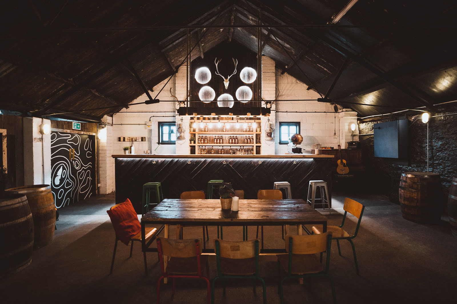 The distillery's tasting room with a bar, a long table and antlers on the wall.