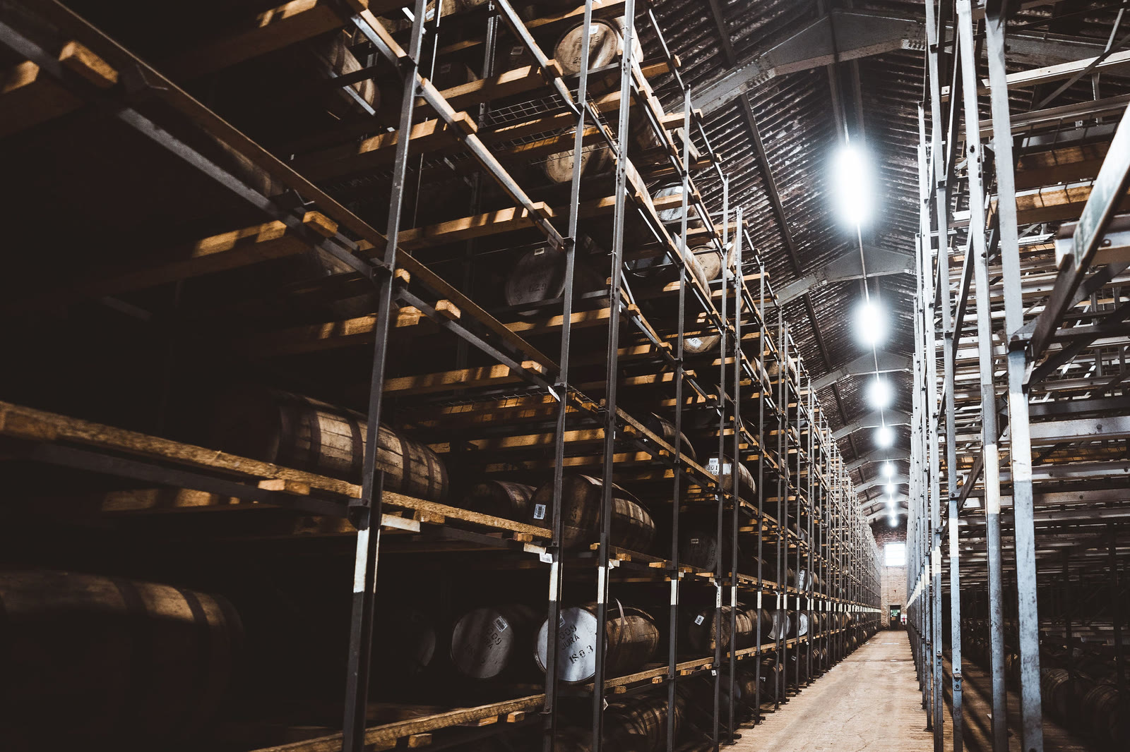 Racks of casks stretching down a long warehouse.