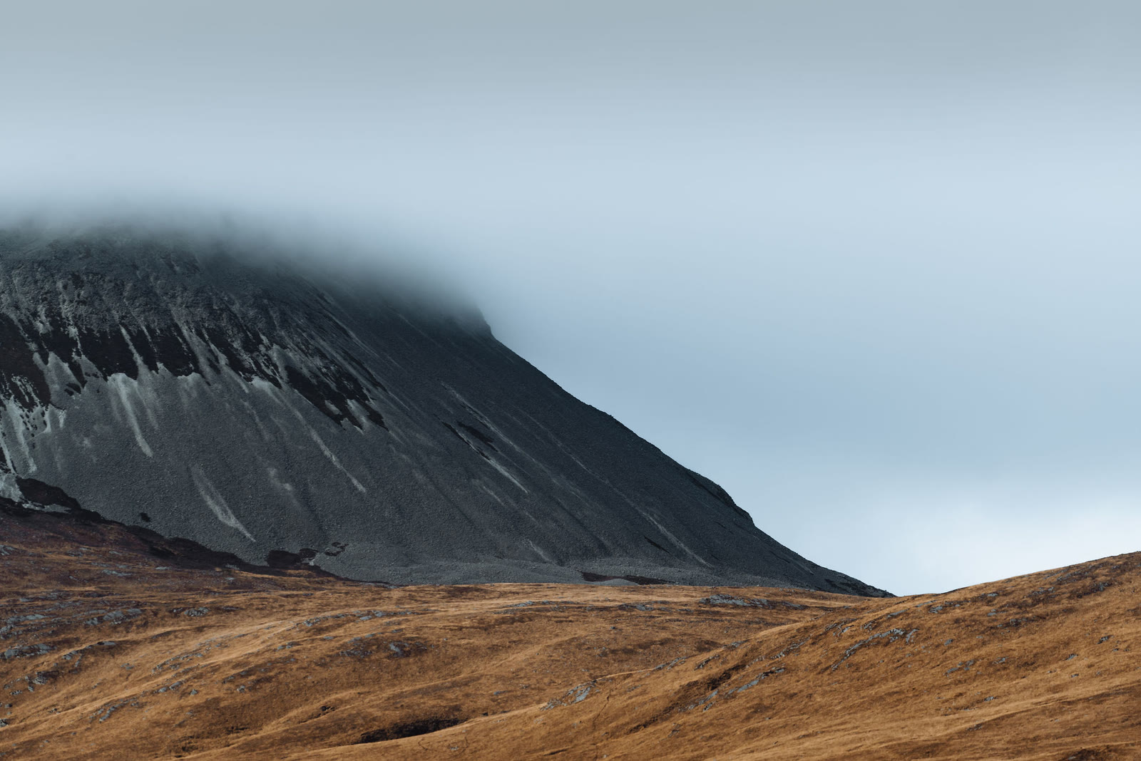 The dark flank of one of the Paps of Jura rising into low cloud.