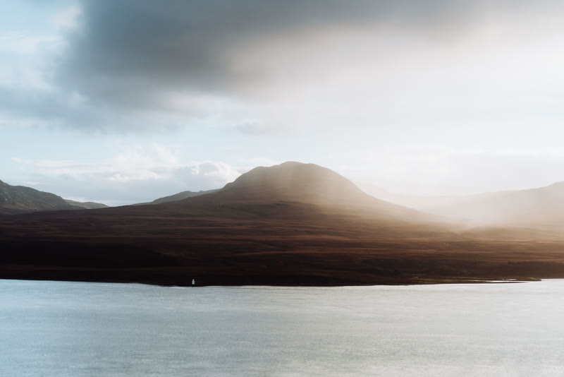 Light breaking through cloud onto one of the Paps of Jura above the water.