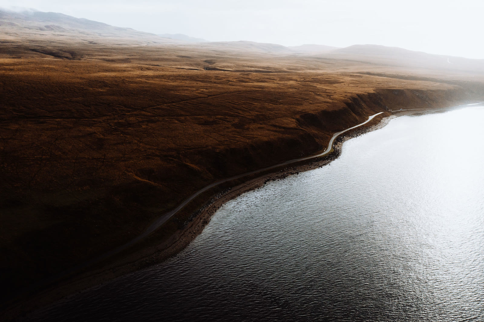 Jura's single road following the shore of the Sound of Islay below brown moorland, from the air.