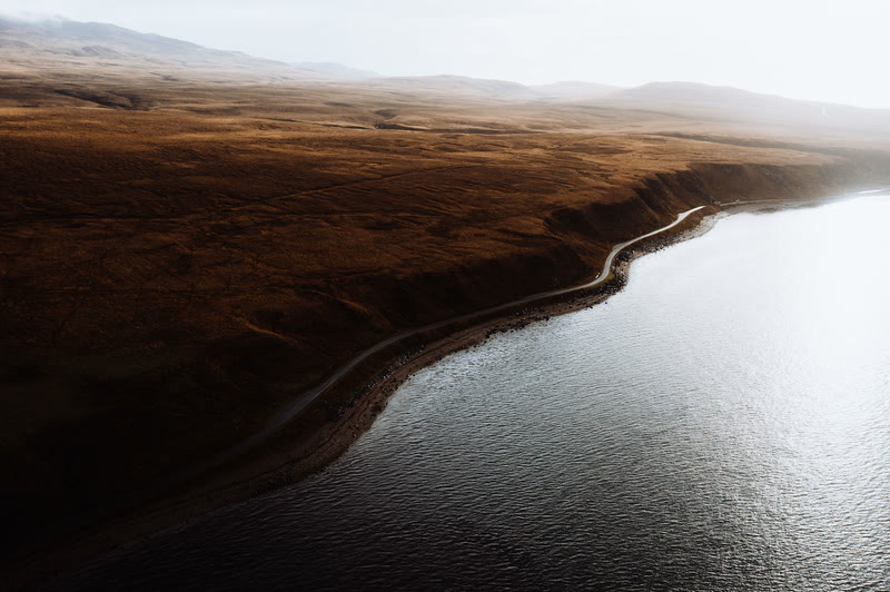Jura's single road following the shore of the Sound of Islay below brown moorland, from the air.