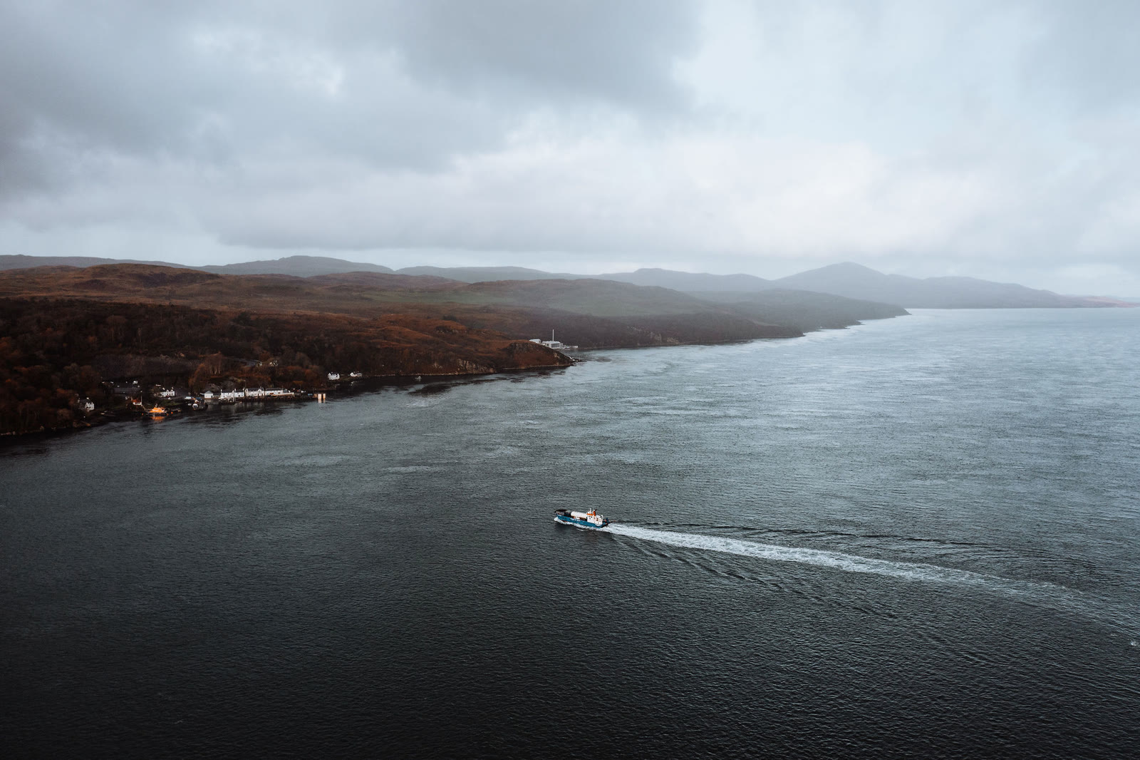 The small ferry crossing the Sound of Islay, houses along the far shore.
