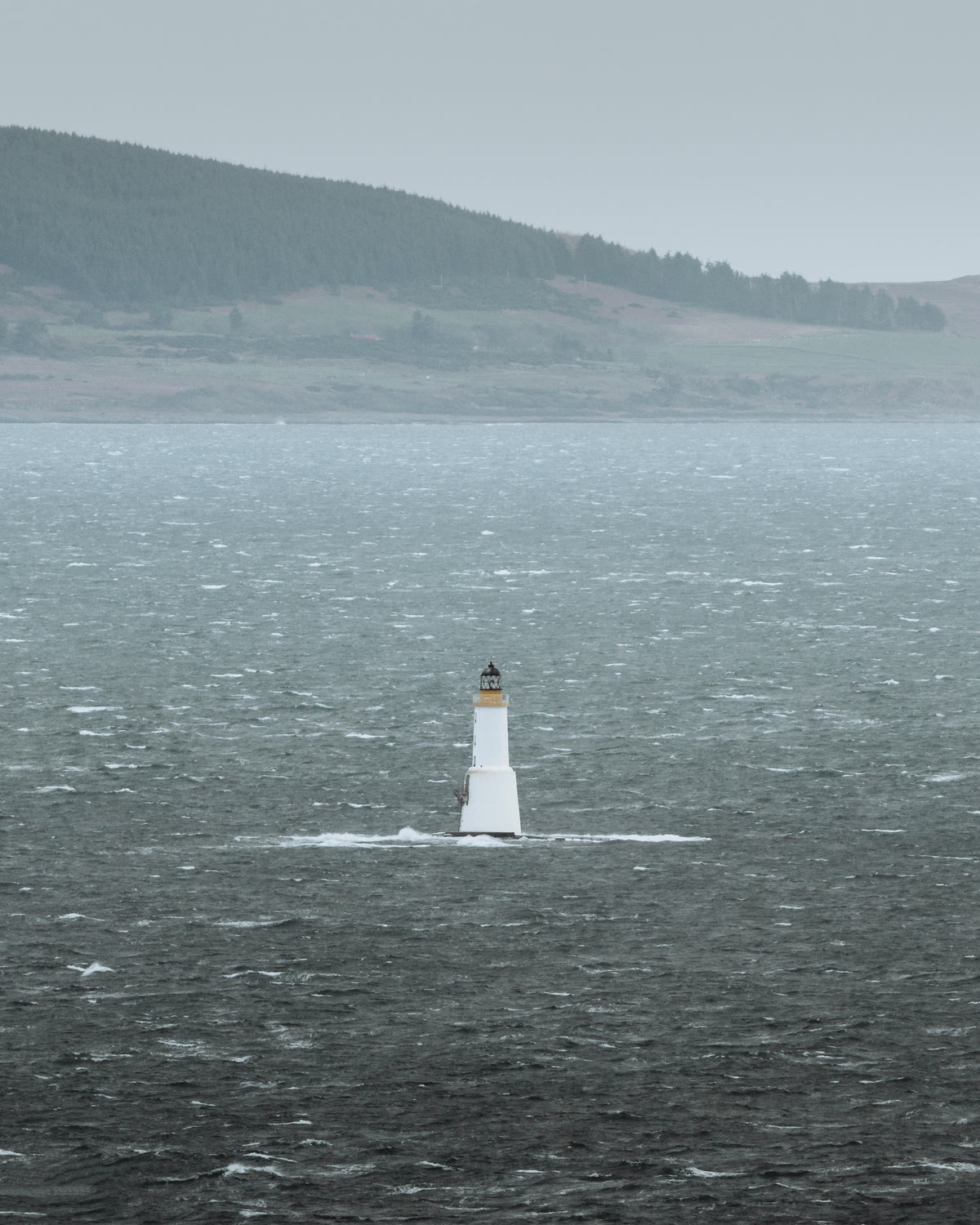 A white lighthouse on its rock in a rough Sound of Jura.