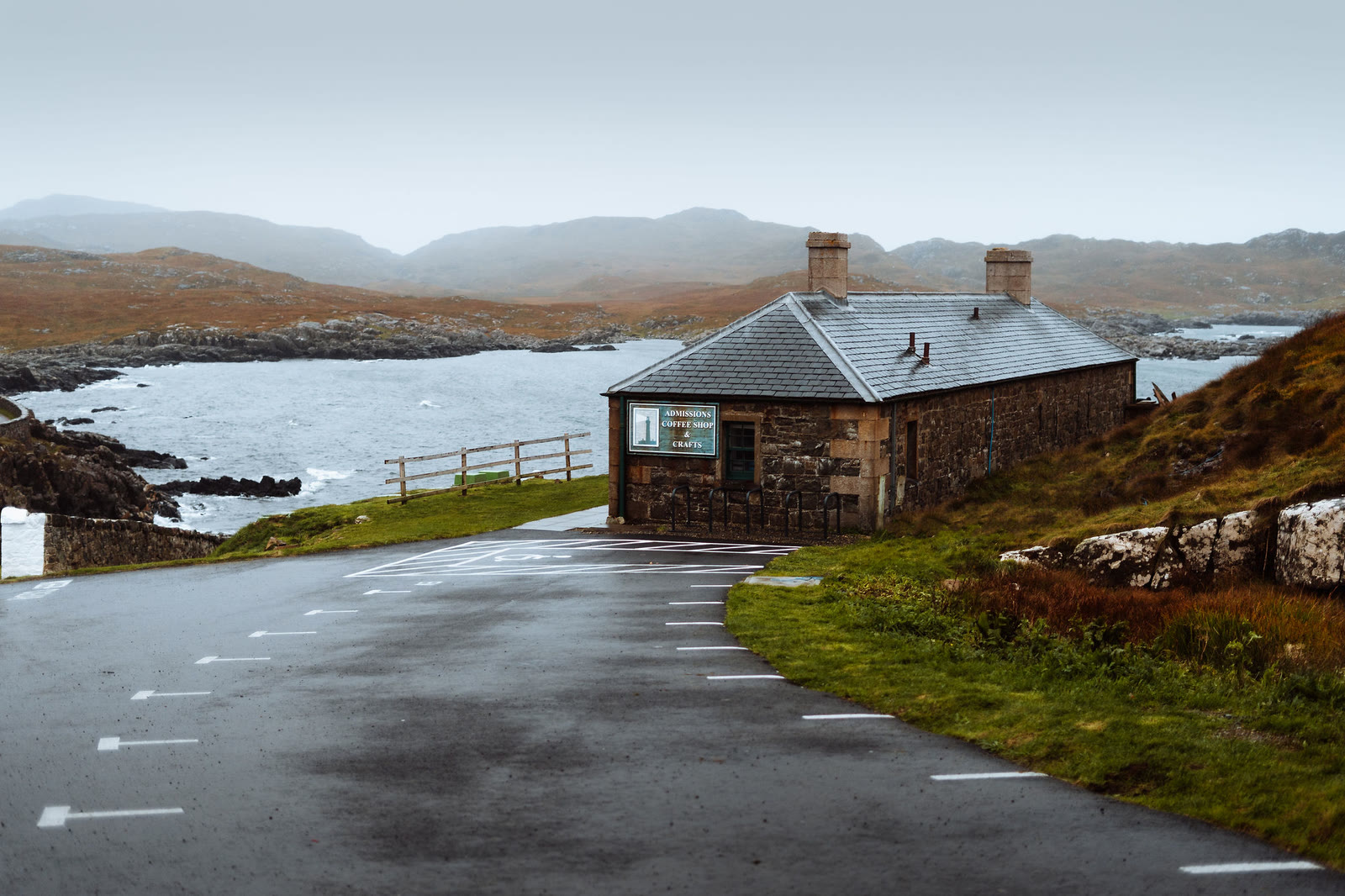 The stone visitor centre below Ardnamurchan Lighthouse, with a rocky bay behind.