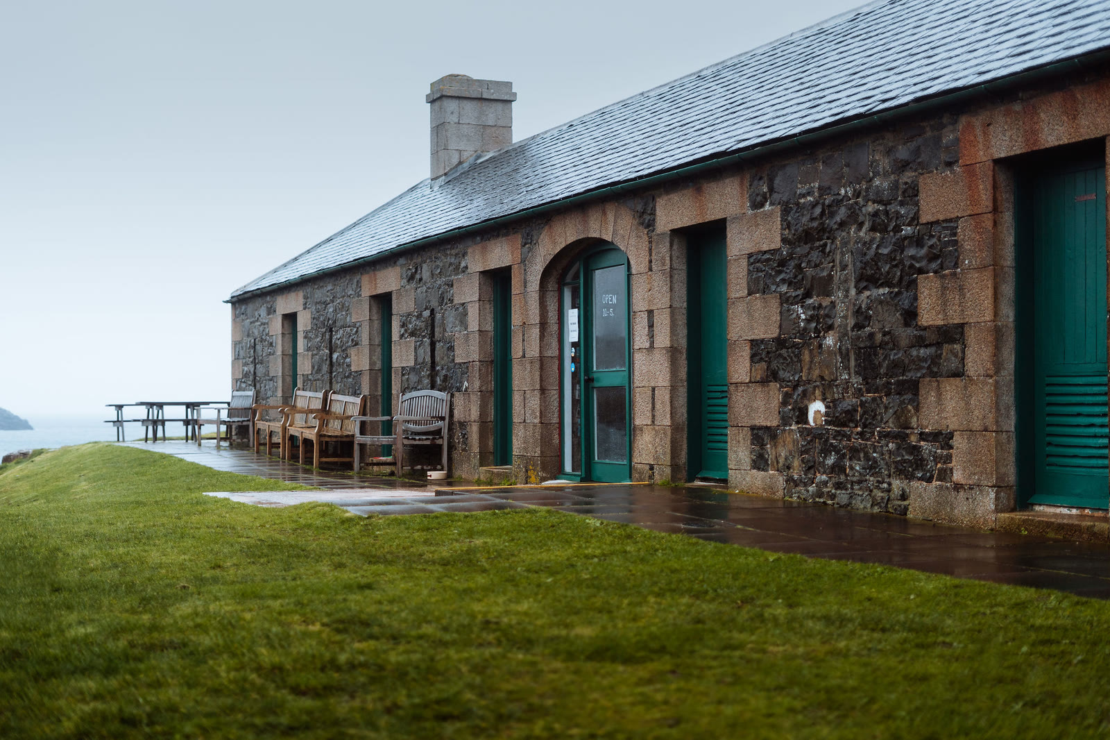 The old stone stables at Ardnamurchan Lighthouse, green doors and benches outside.