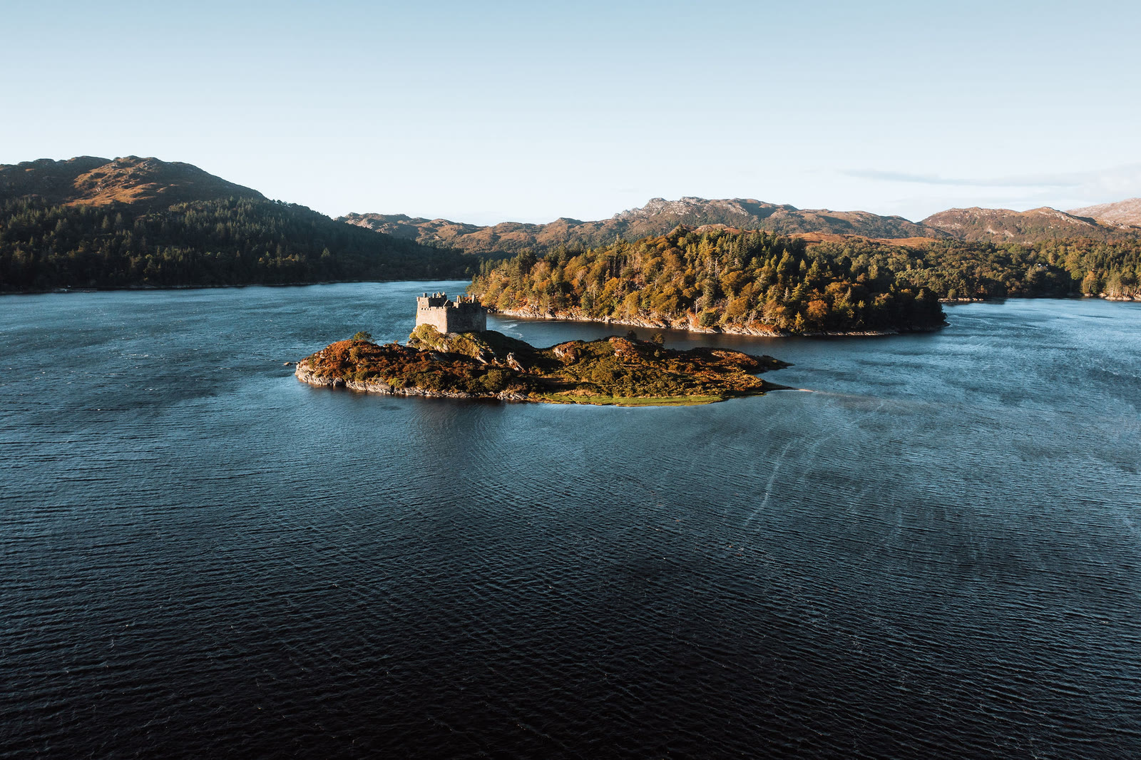 Castle Tioram on its tidal island in Loch Moidart, seen from the air with wooded islands behind.