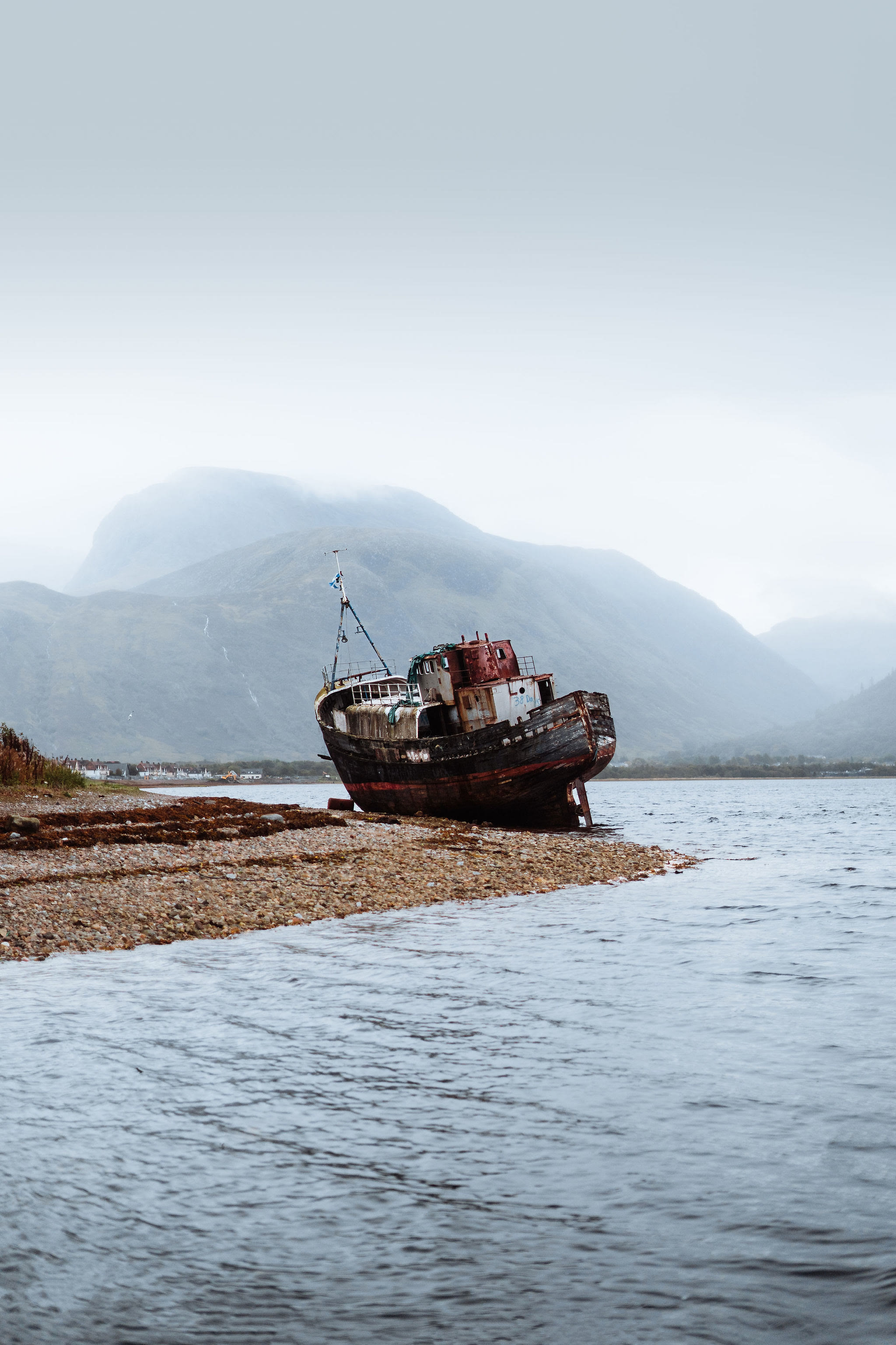 The Corpach wreck on its shingle with the bulk of Ben Nevis behind, its top in cloud.
