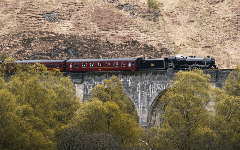 The Jacobite's black engine and maroon carriages on the arches of the Glenfinnan Viaduct.