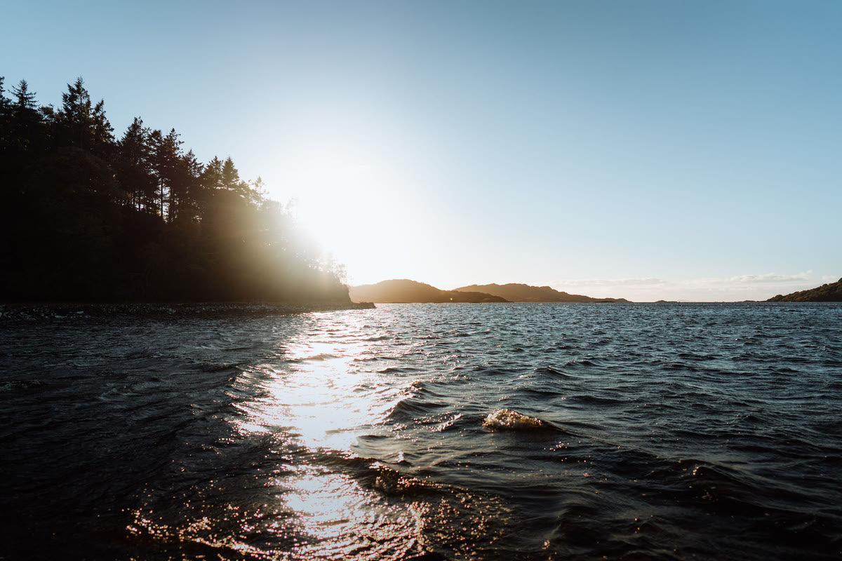 The sun setting behind a wooded point on Loch Moidart.