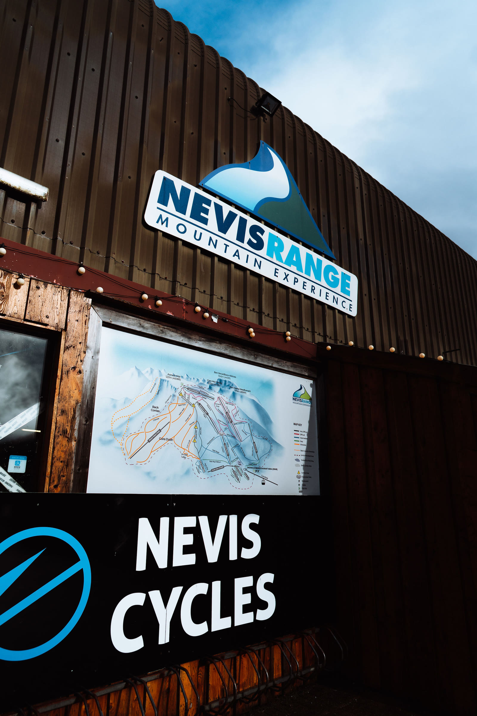 The Nevis Range and Nevis Cycles signs beside a piste map on the base building.