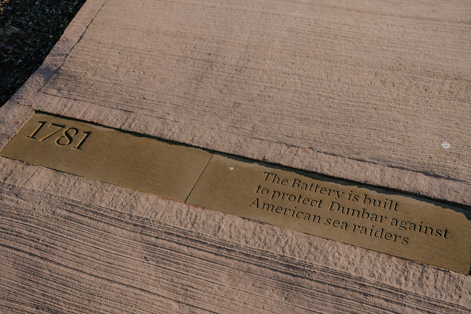 A bronze plaque set into paving reads "1781, The Battery is built to protect Dunbar against American sea raiders".