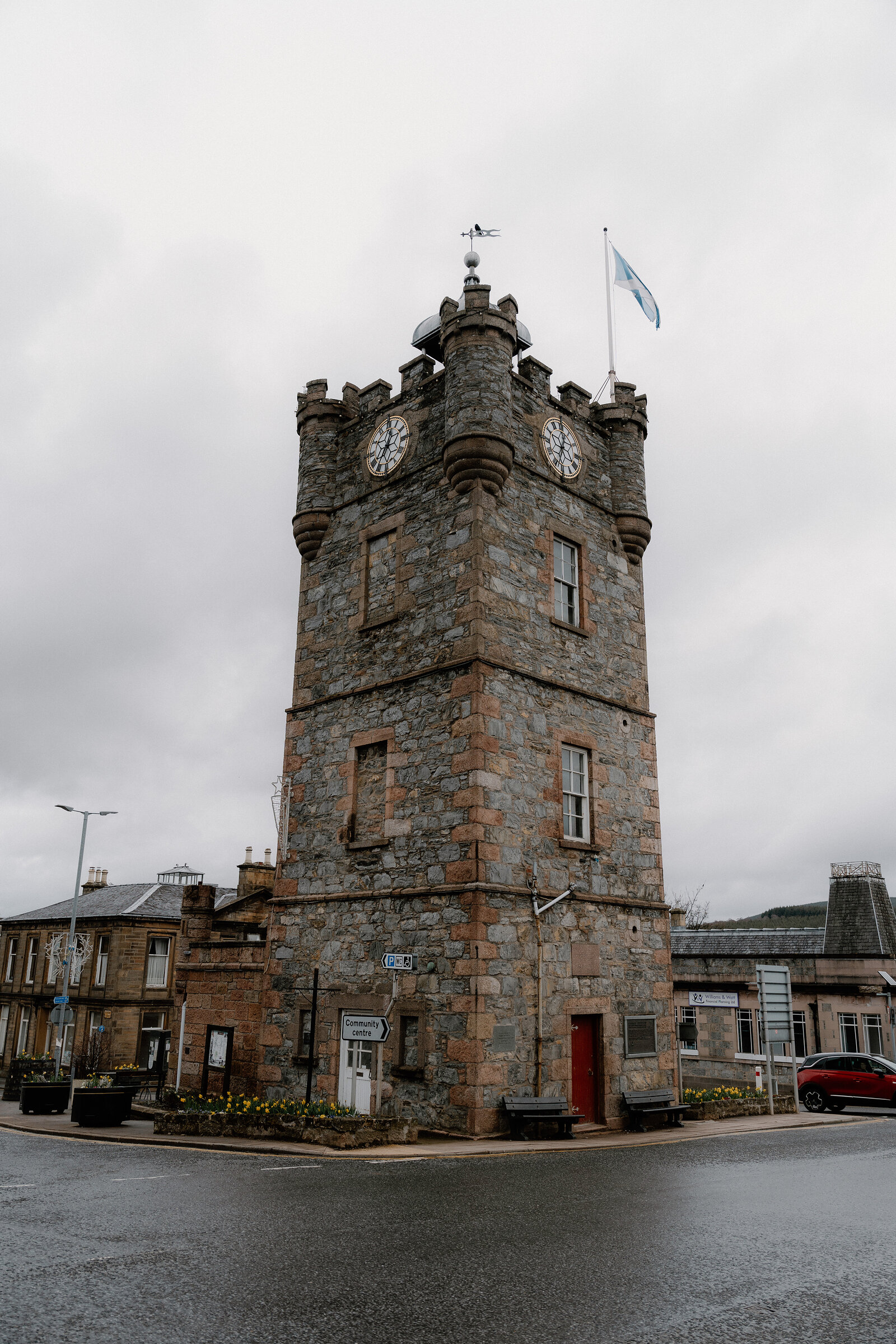A castellated clock tower with a Saltire flag stands at a crossroads in Dufftown.
