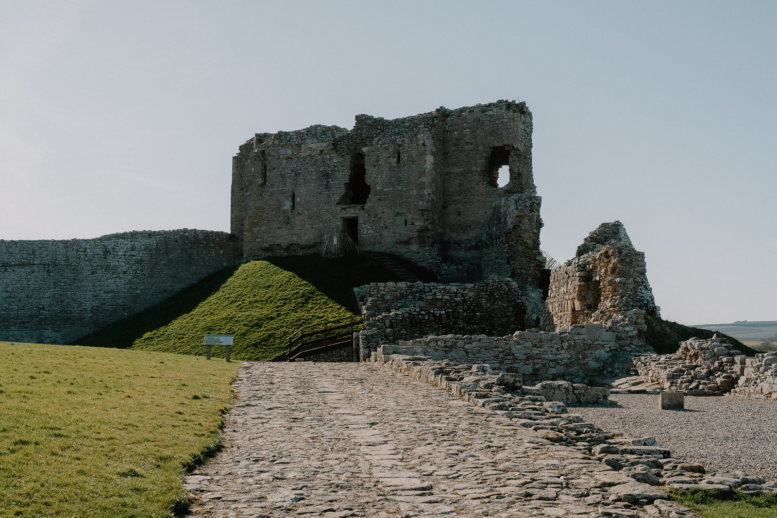 A stone path leads up to Duffus Castle's ruined keep past a grassy motte and bailey walls.