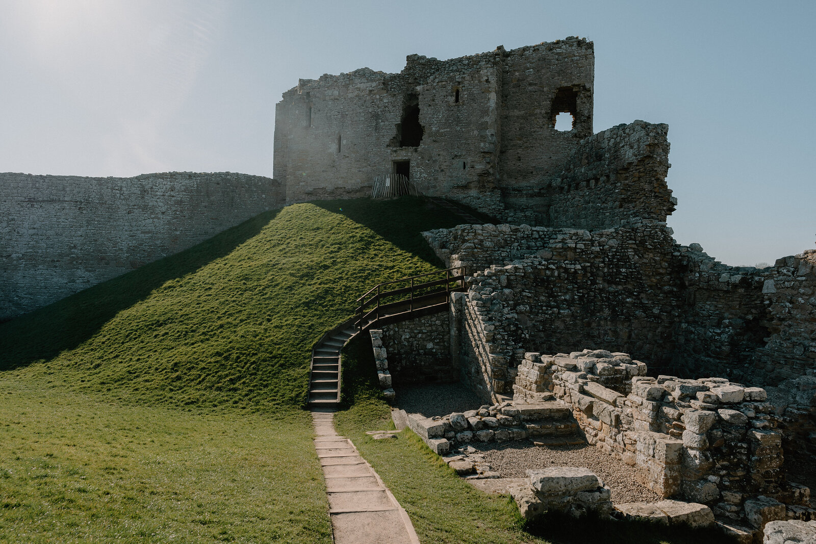 A stone path leads past Duffus Castle's grassy motte toward its ruined keep and bailey ruins.